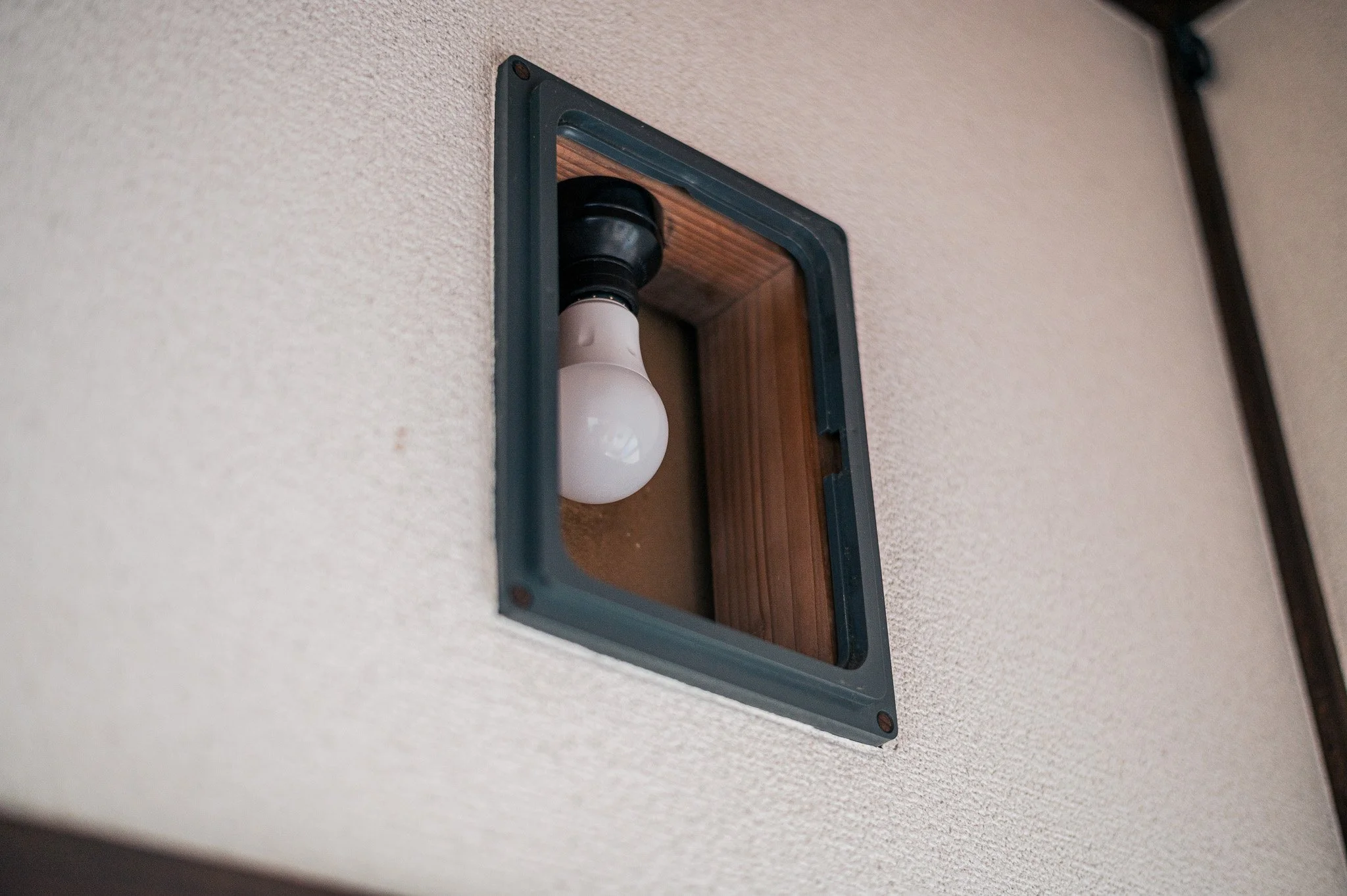 壁の照明ソケットと電球。壁のカバーと木製のベースが見える。