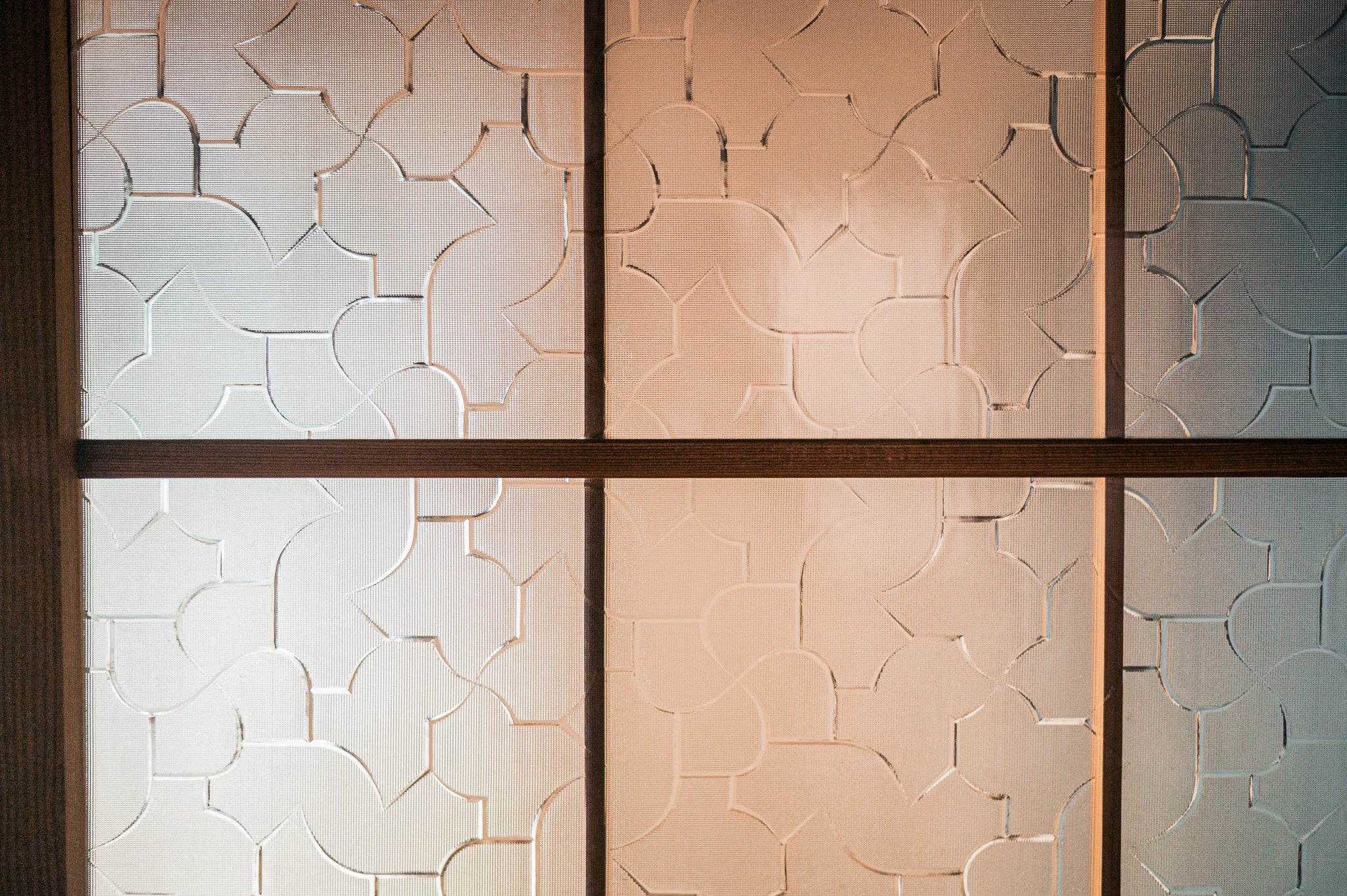 木製の格子に囲まれた白い壁のパネル。幾何学模様のデザインが施されている。