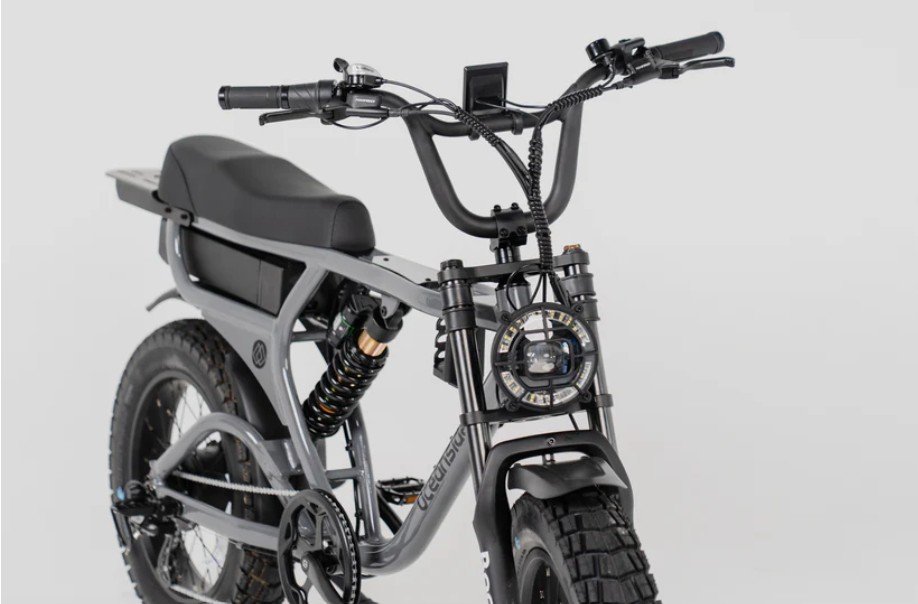 Electric mountain bike with a black frame, suspension, and knobby tires, set against a plain gray background.