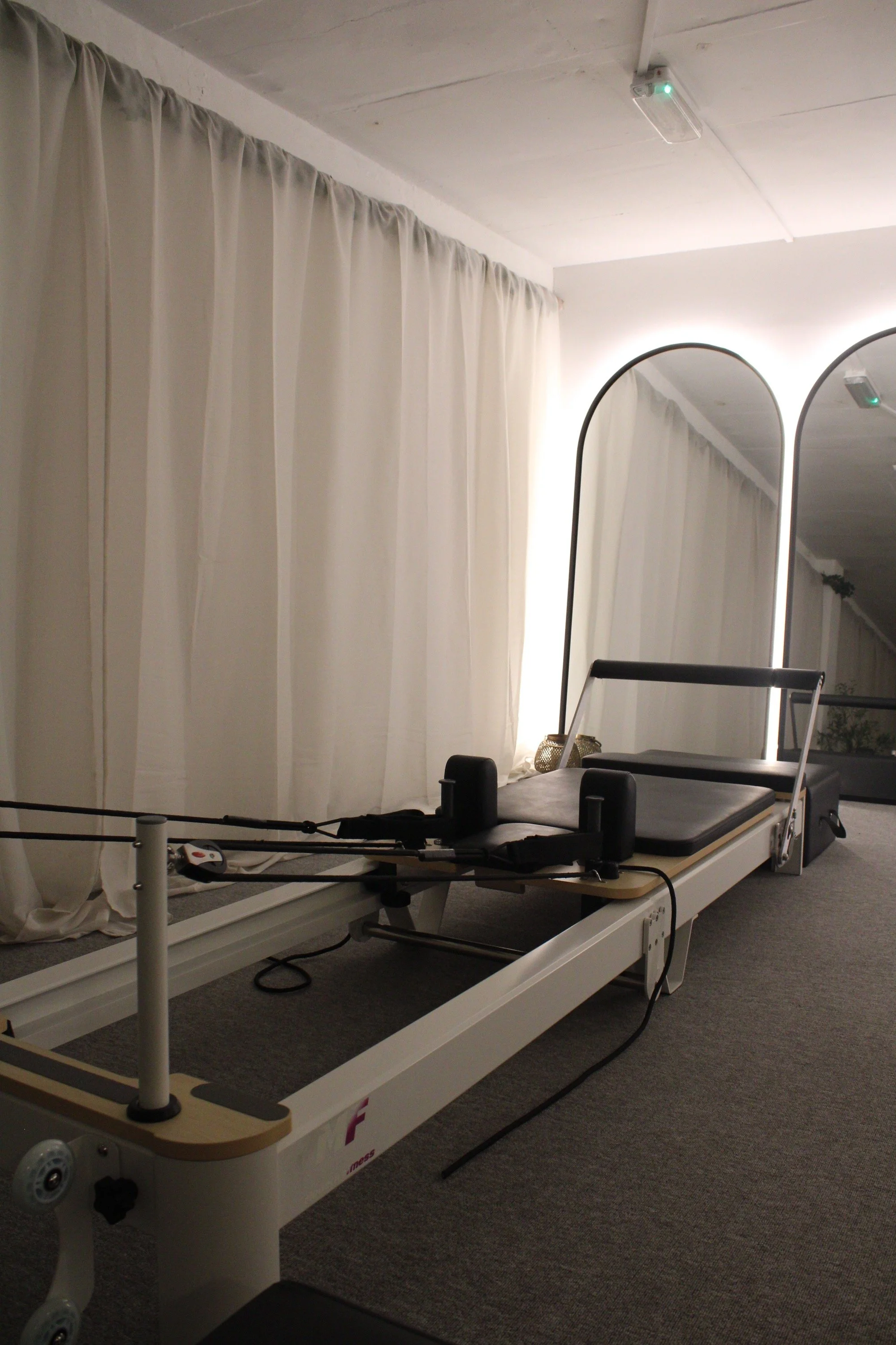 A medical or therapy bed with adjustable features in a room with white curtains and arched mirrors.