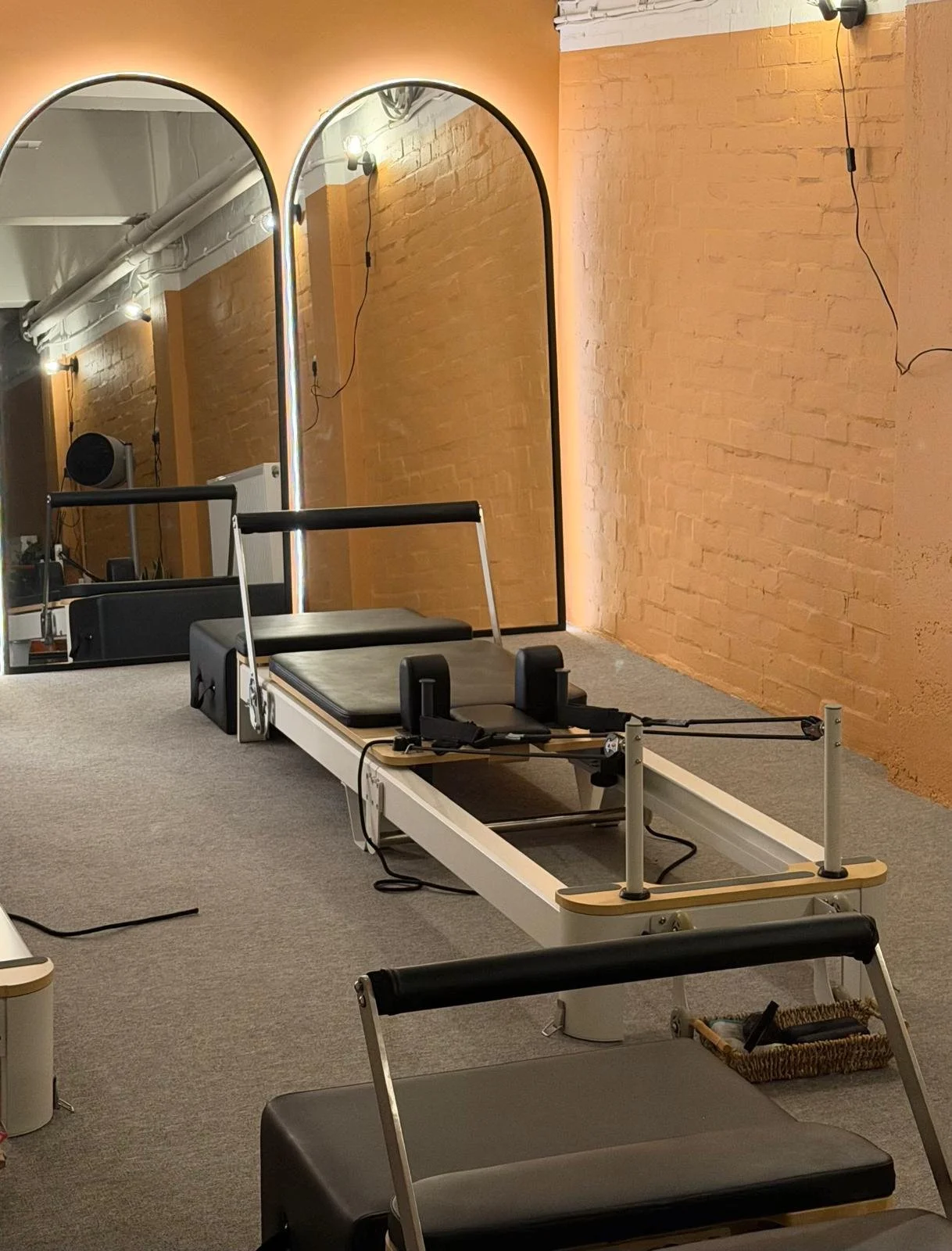Pilates reformer located in a fitness studio with brick walls, mirror, and warm lighting.