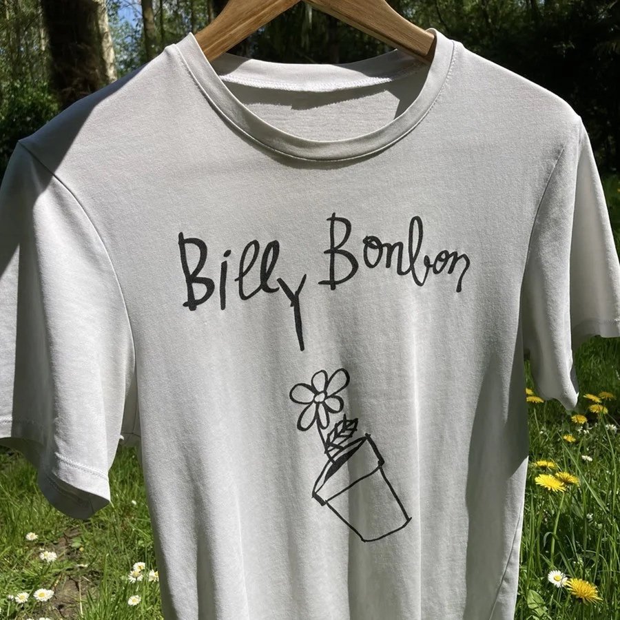 White T-shirt with black handwritten text 'Billy Bonbon' and a drawing of a flower in a tilted pot hanging from a plant.