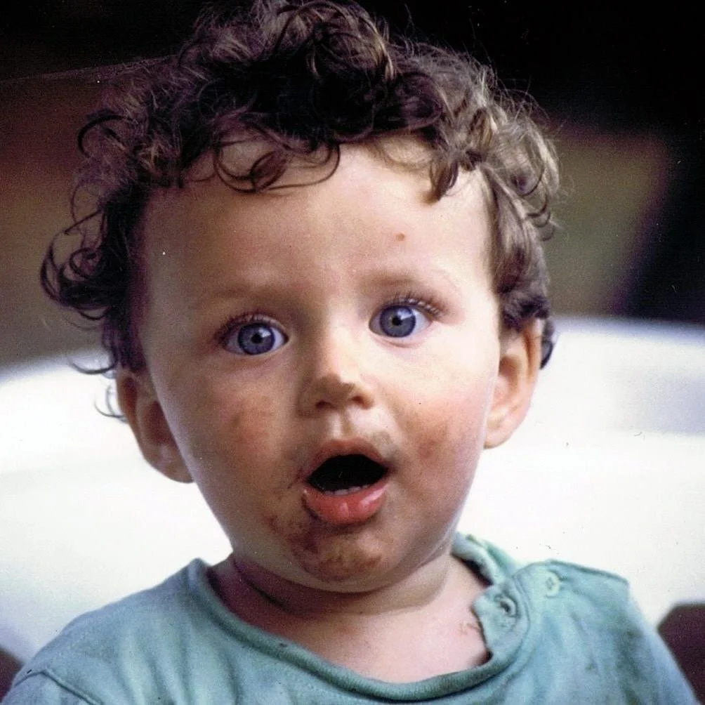 Félix Martinaud as a surprised young child with curly hair and blue eyes, with dirt marks on face and a dirty mouth.