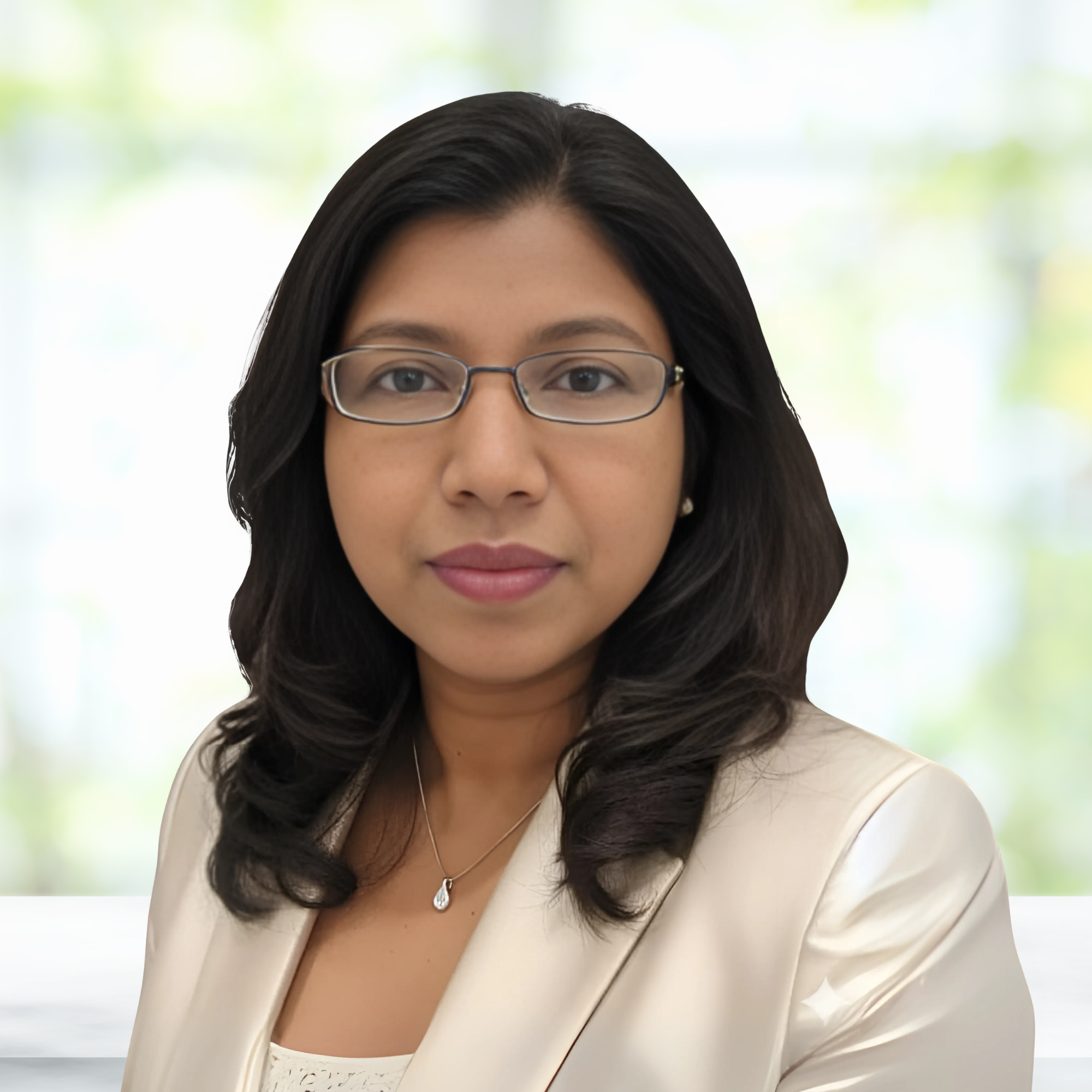 Professional woman with glasses and dark wavy hair, wearing a cream blazer and a delicate necklace, standing in front of a blurred outdoor background.