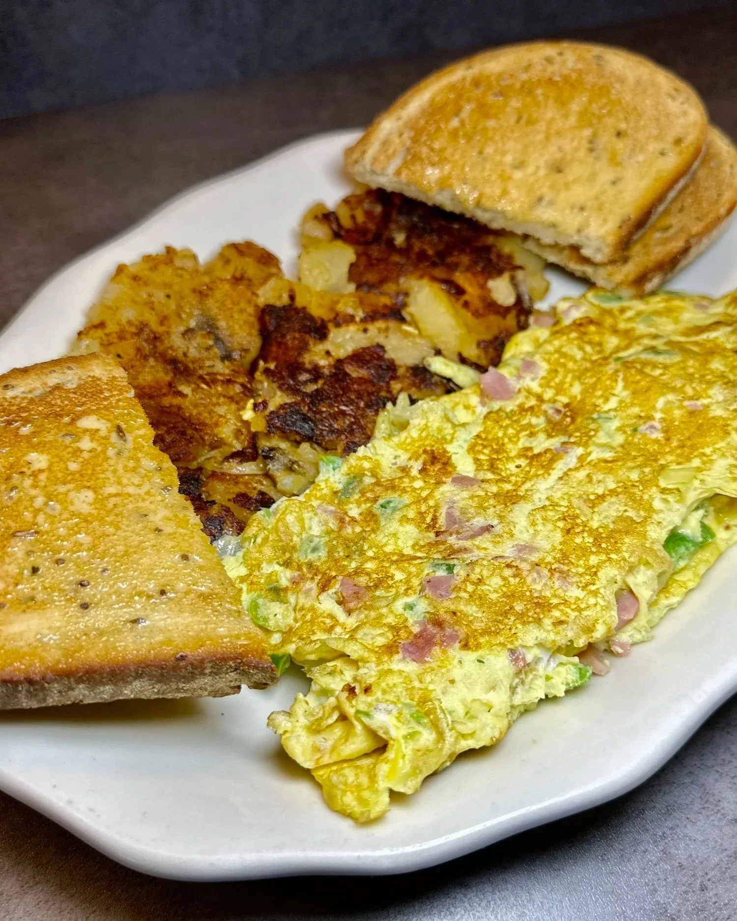 Fried breakfast plate with scrambled eggs, toasted bread, hash browns, and French toast.