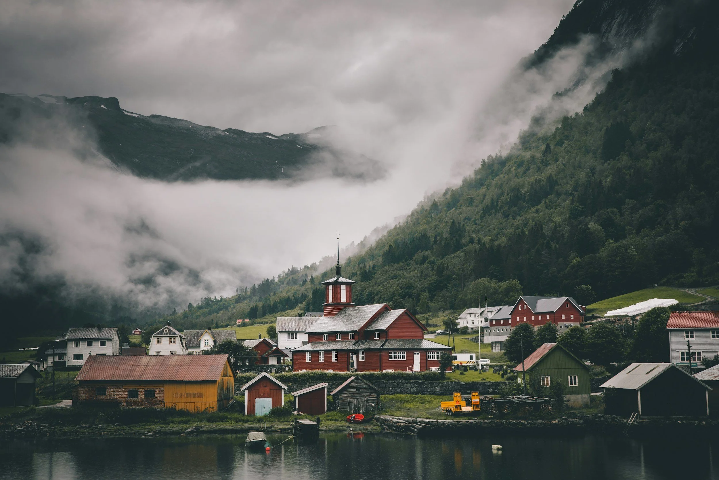 Quiet Norwegian fjord village with colourful houses mountains and low clouds showing why visiting Norway in May or September offers fewer tourists and peaceful authentic travel experiences