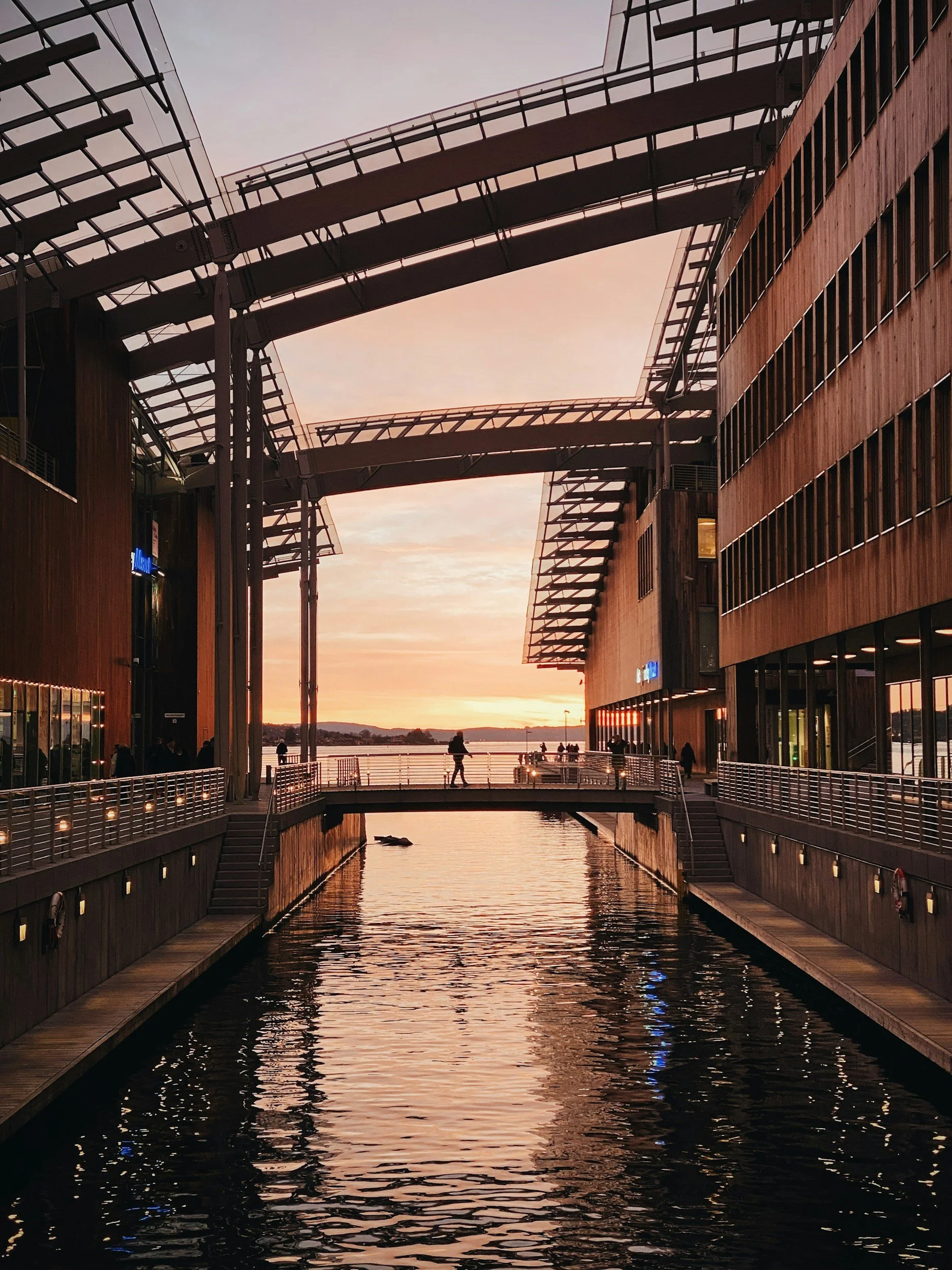 A picture of a person walking across the bridge outside at the Astrup Fearnley museum in Oslo.