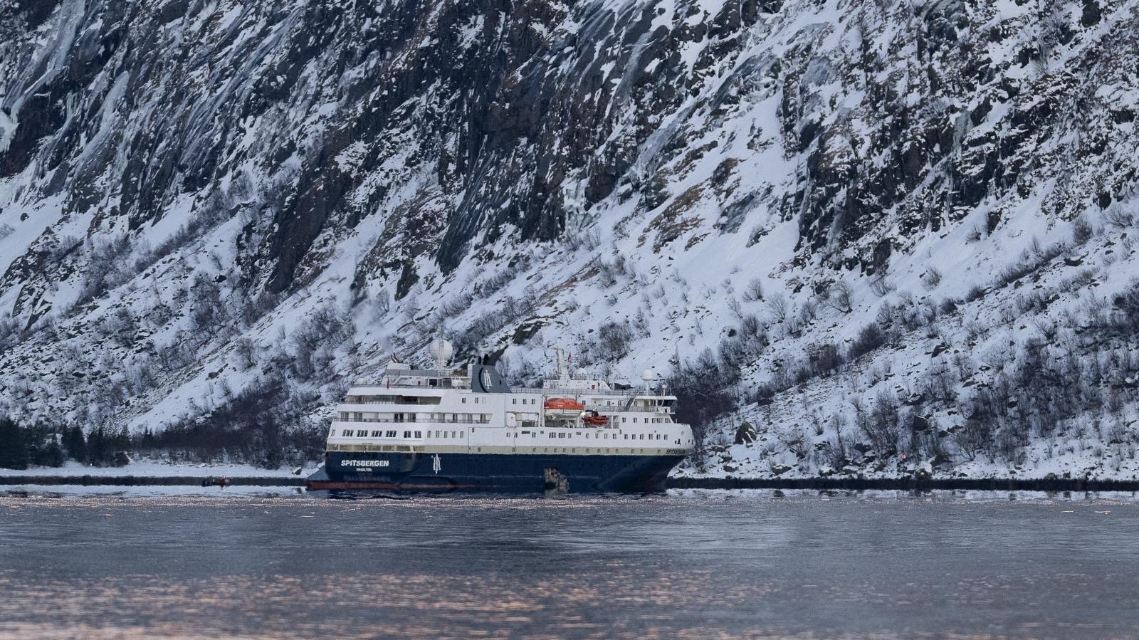 HX expedition ship Spitsbergen sailing the Northern Norwegian coast in winter with snow-covered mountains.