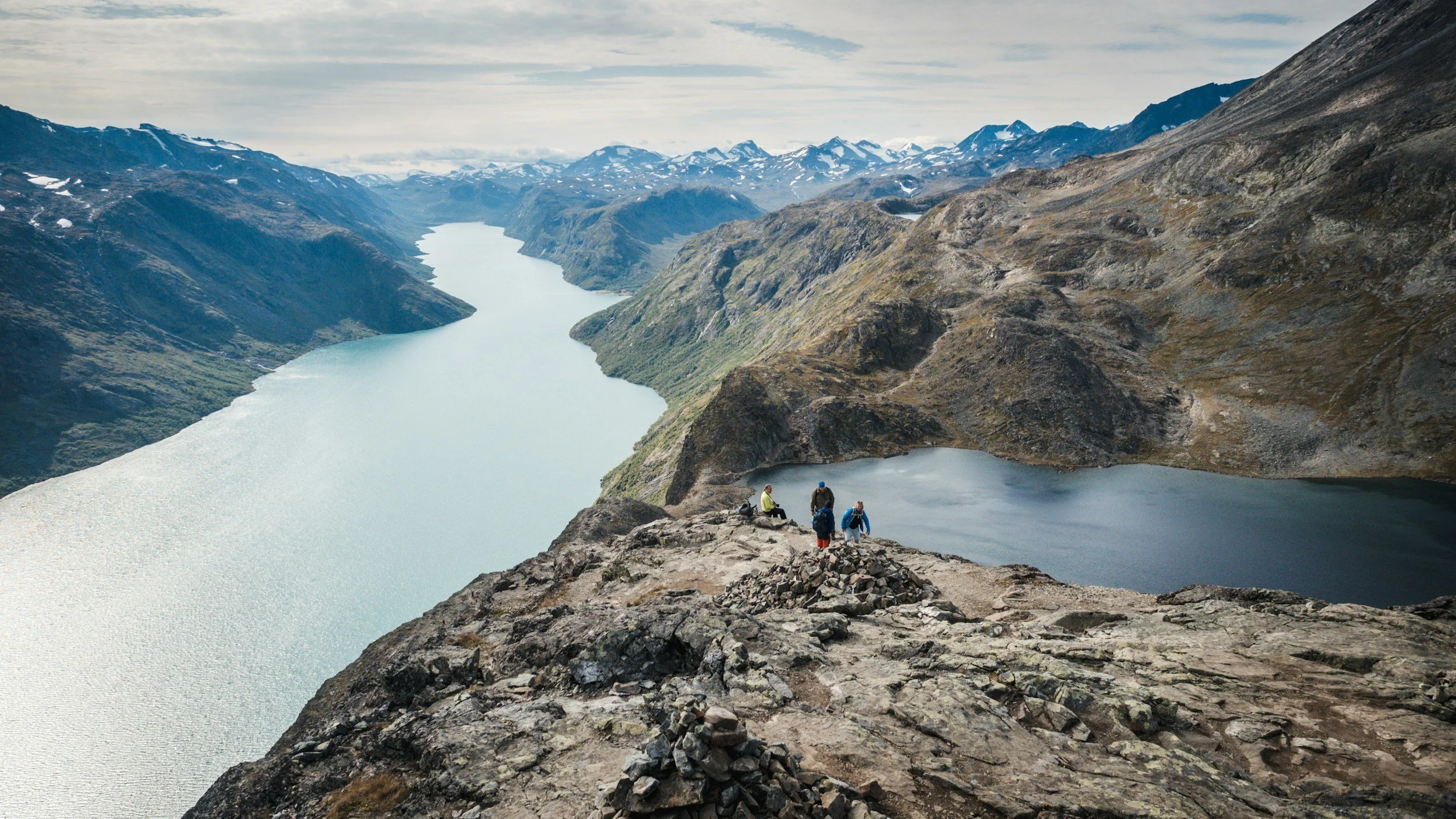 Hikers climbing Besseggen, with the lake in the background.
