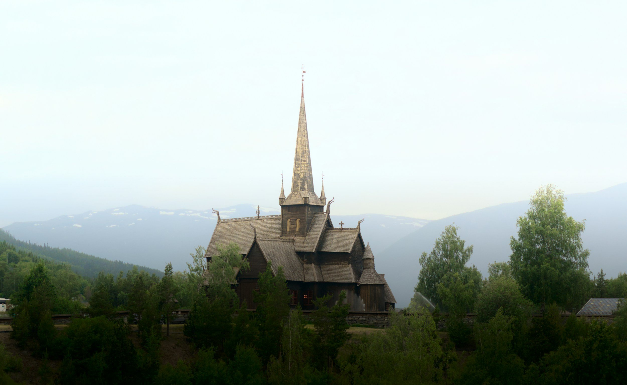 A picture of Lom Stave Church with misty mountains in the background.