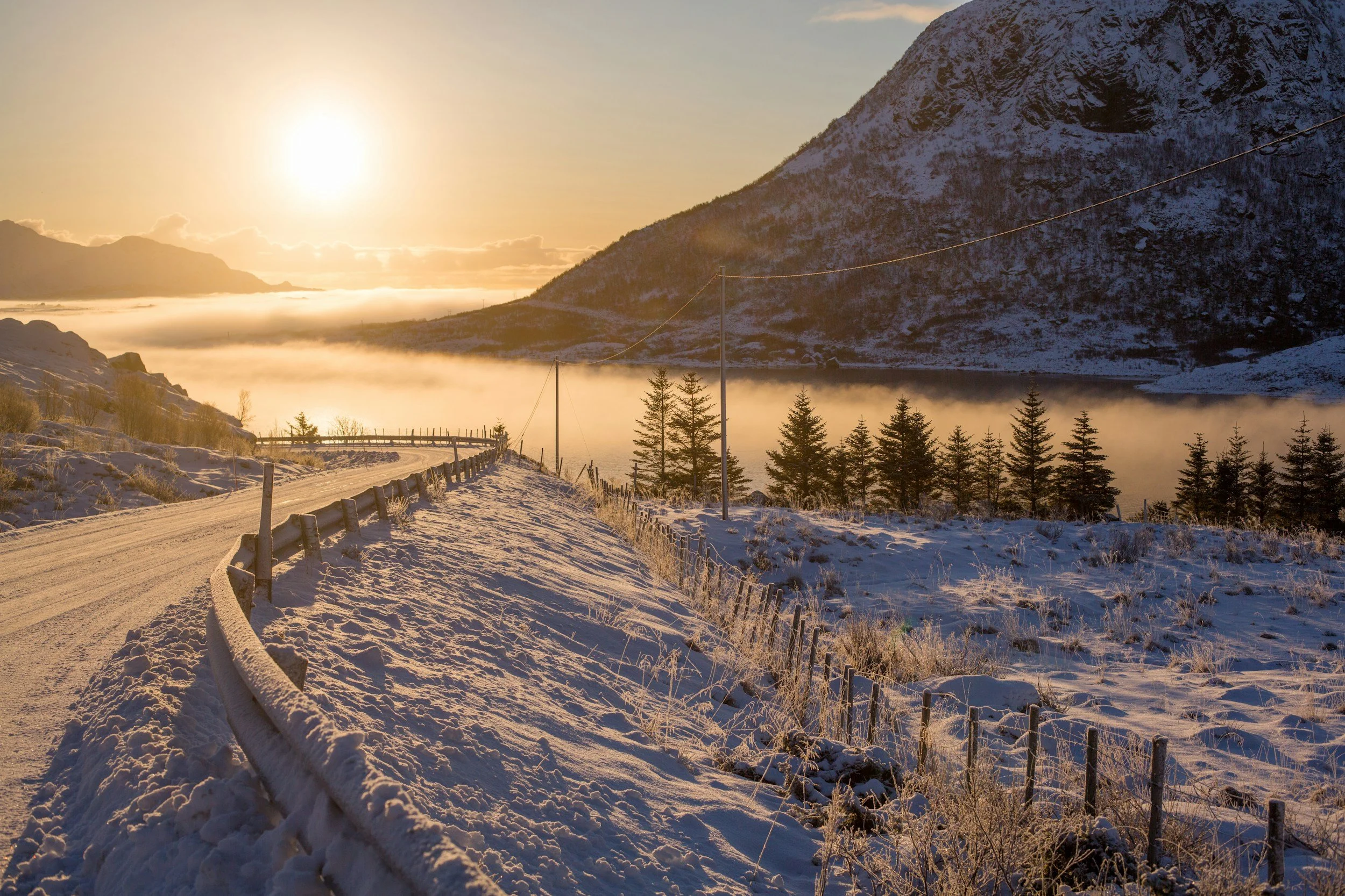 snow covered road and snow covered mountains during the sunset in norway.