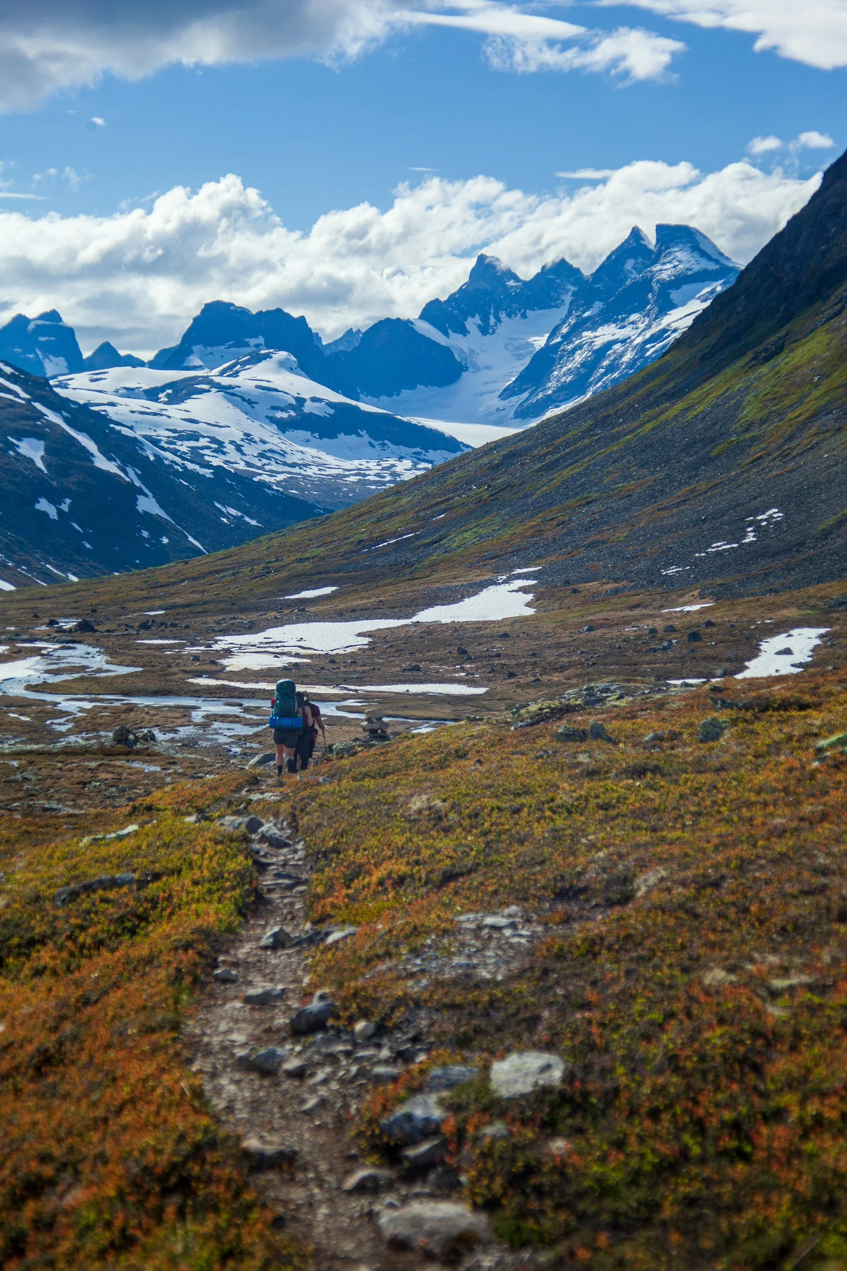 Hikers in Jotunheimen, Norway. Its summer but the mountain peaks are covered in snow.