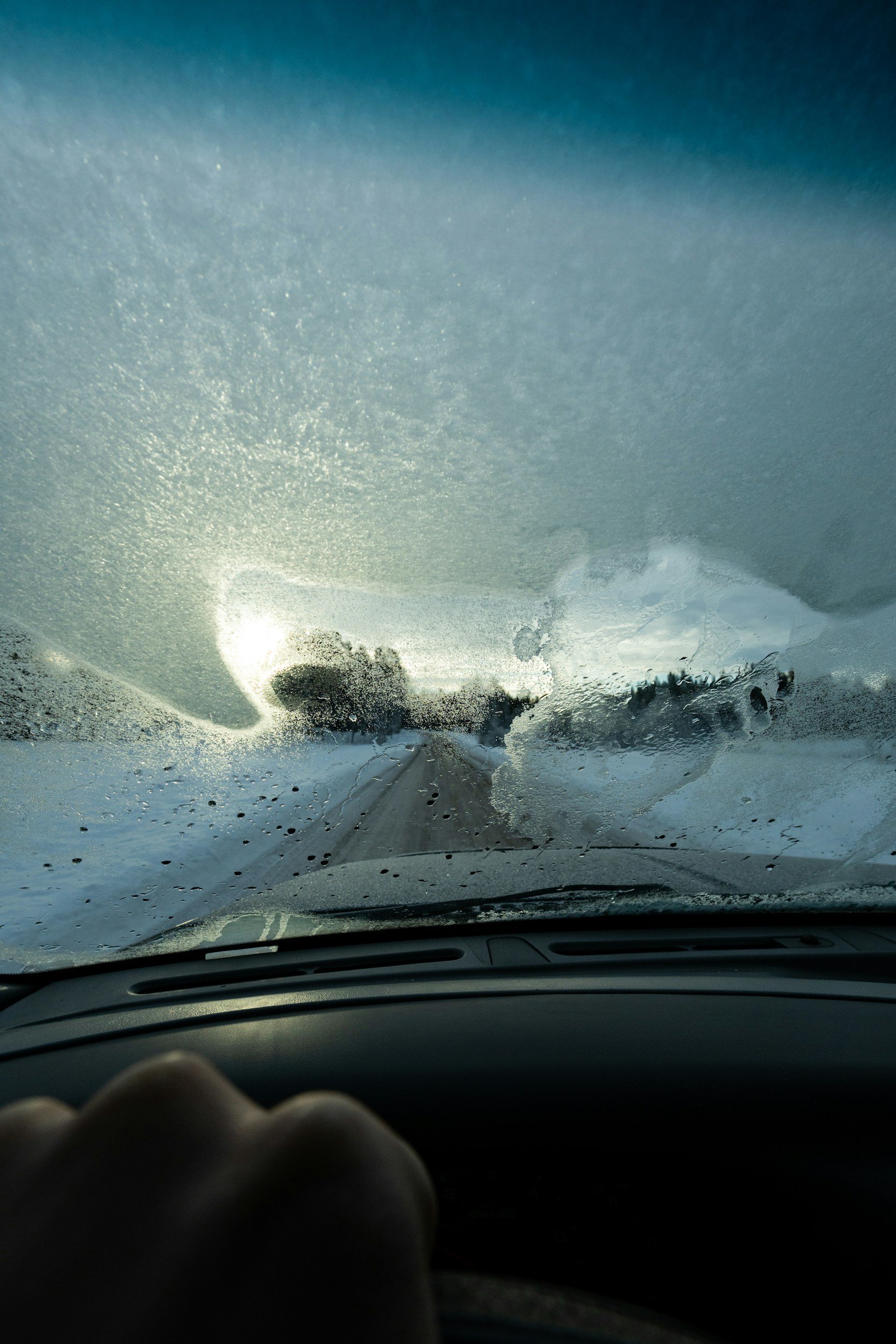 A picture from inside the car, the window is covered in snow and ice.