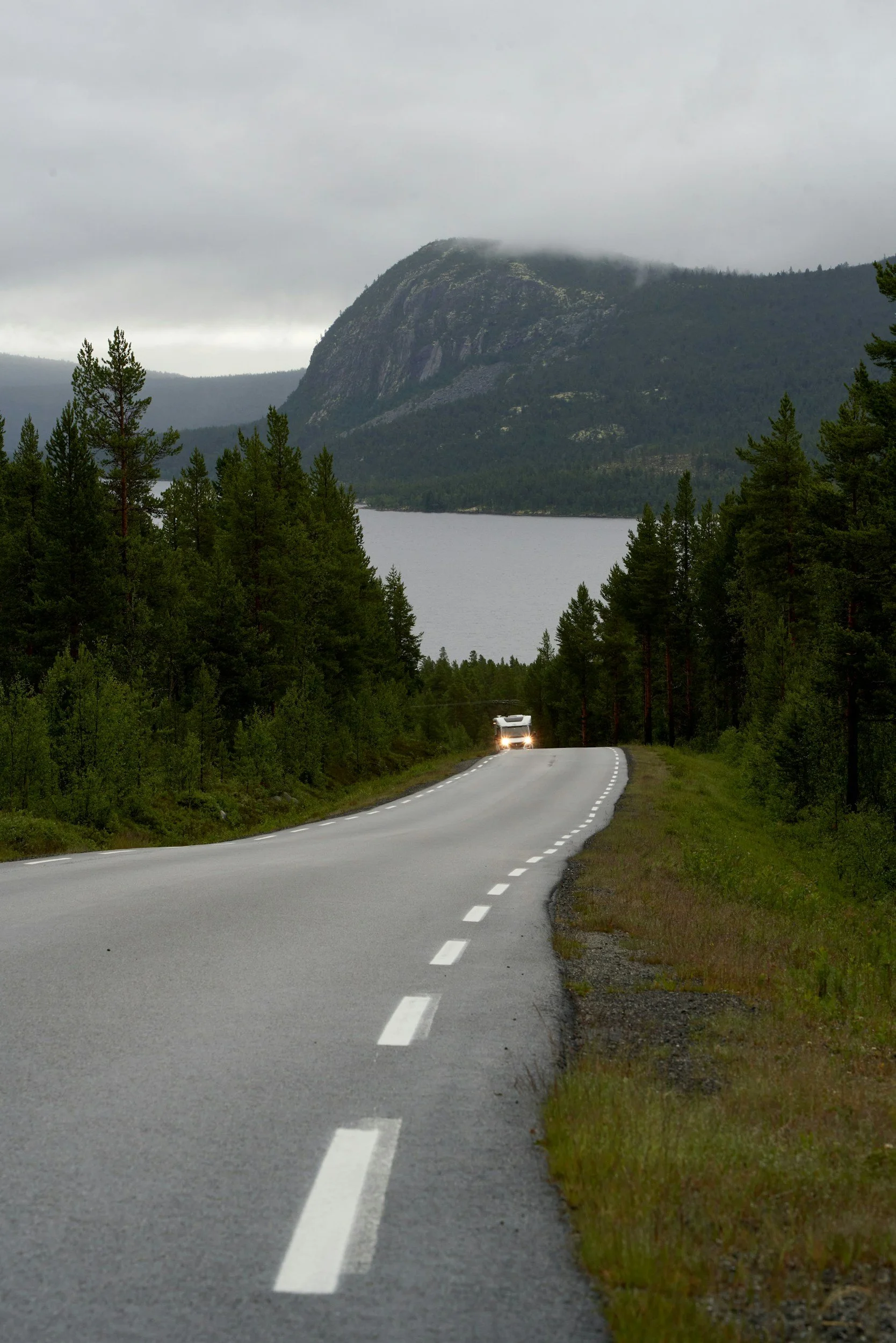 A picture of a car driving on a curvy road in Norway.