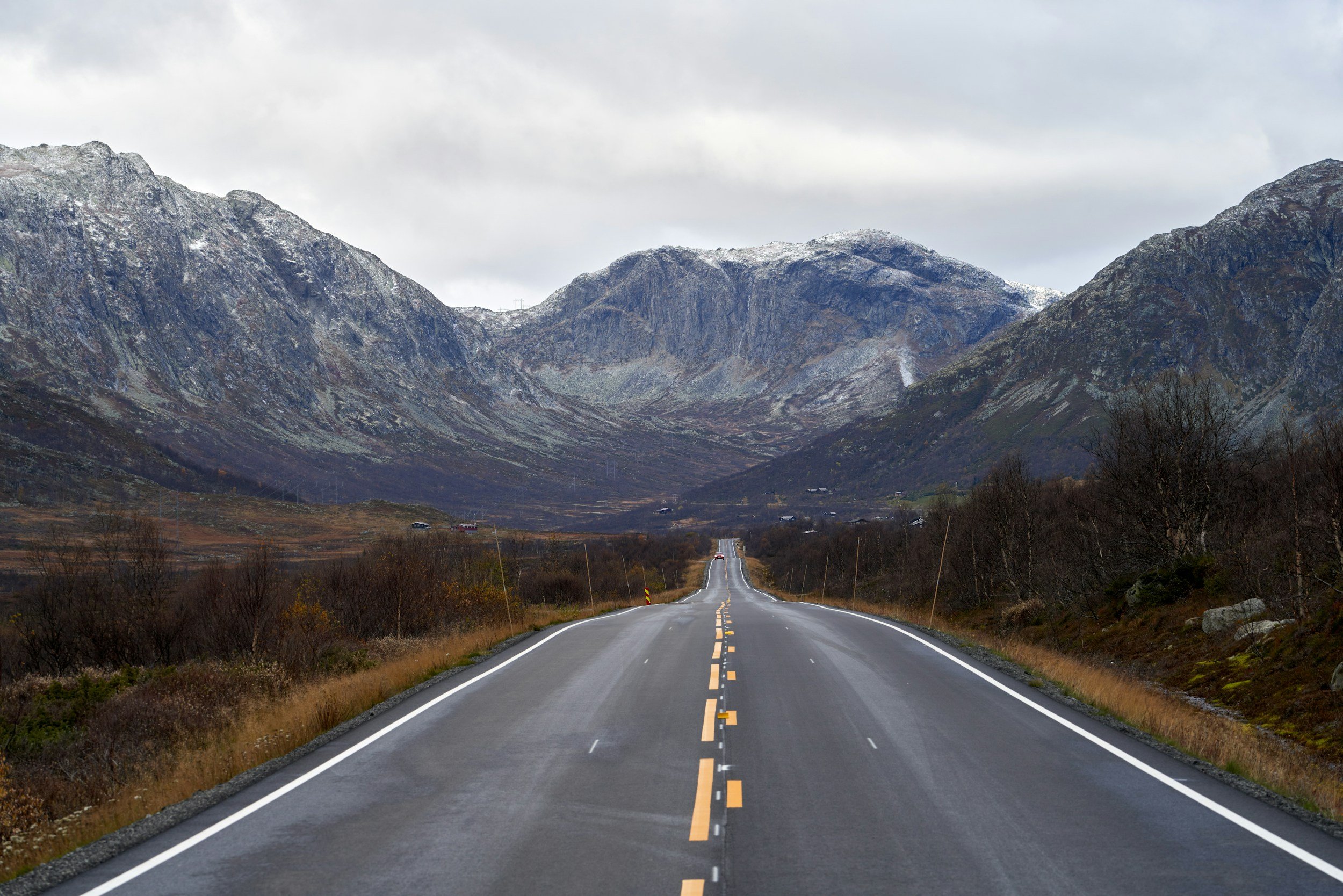 A picture of a road in Norway with mountains stretching around it.