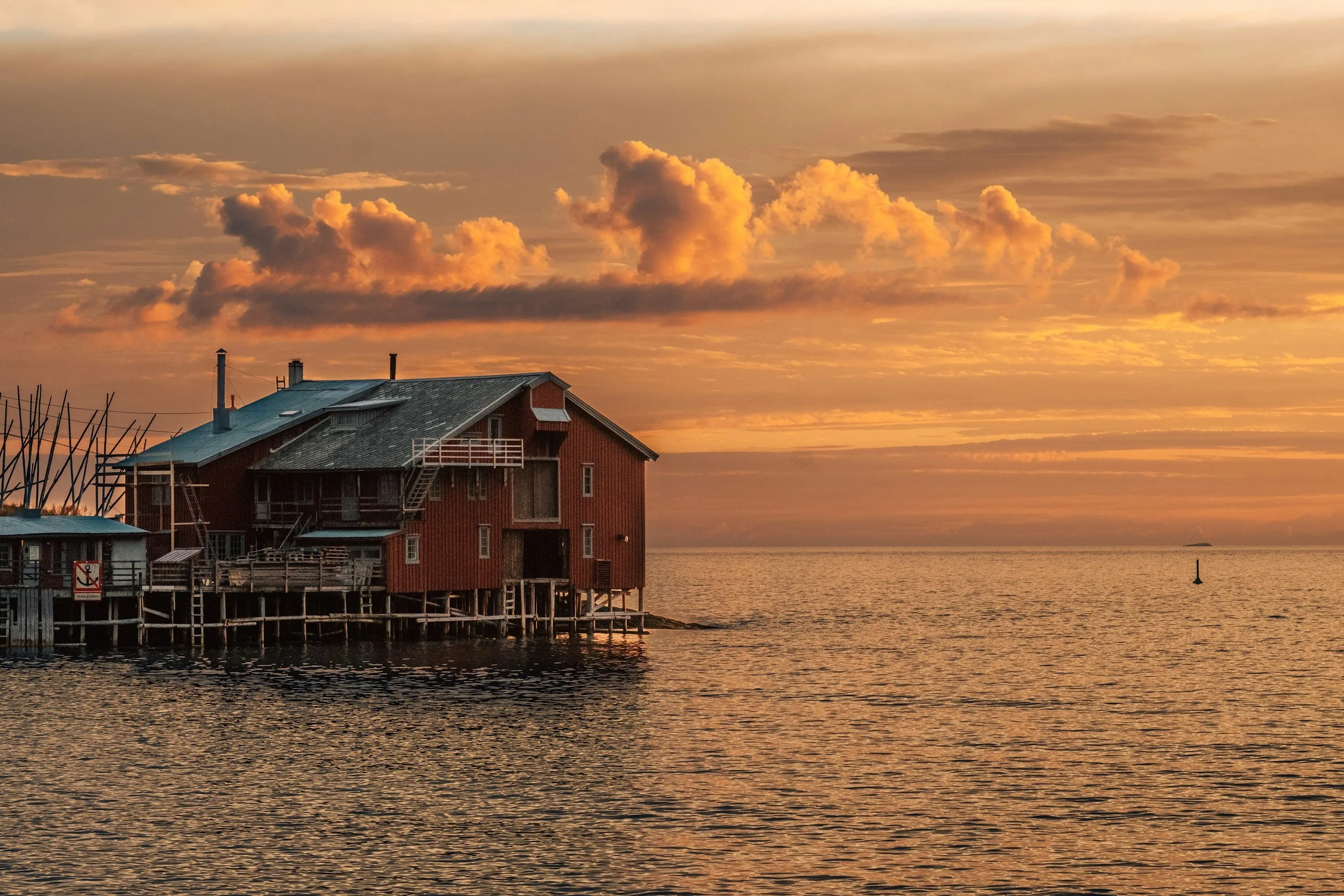 A picture of a hotel in Senja on the water in the sunset.