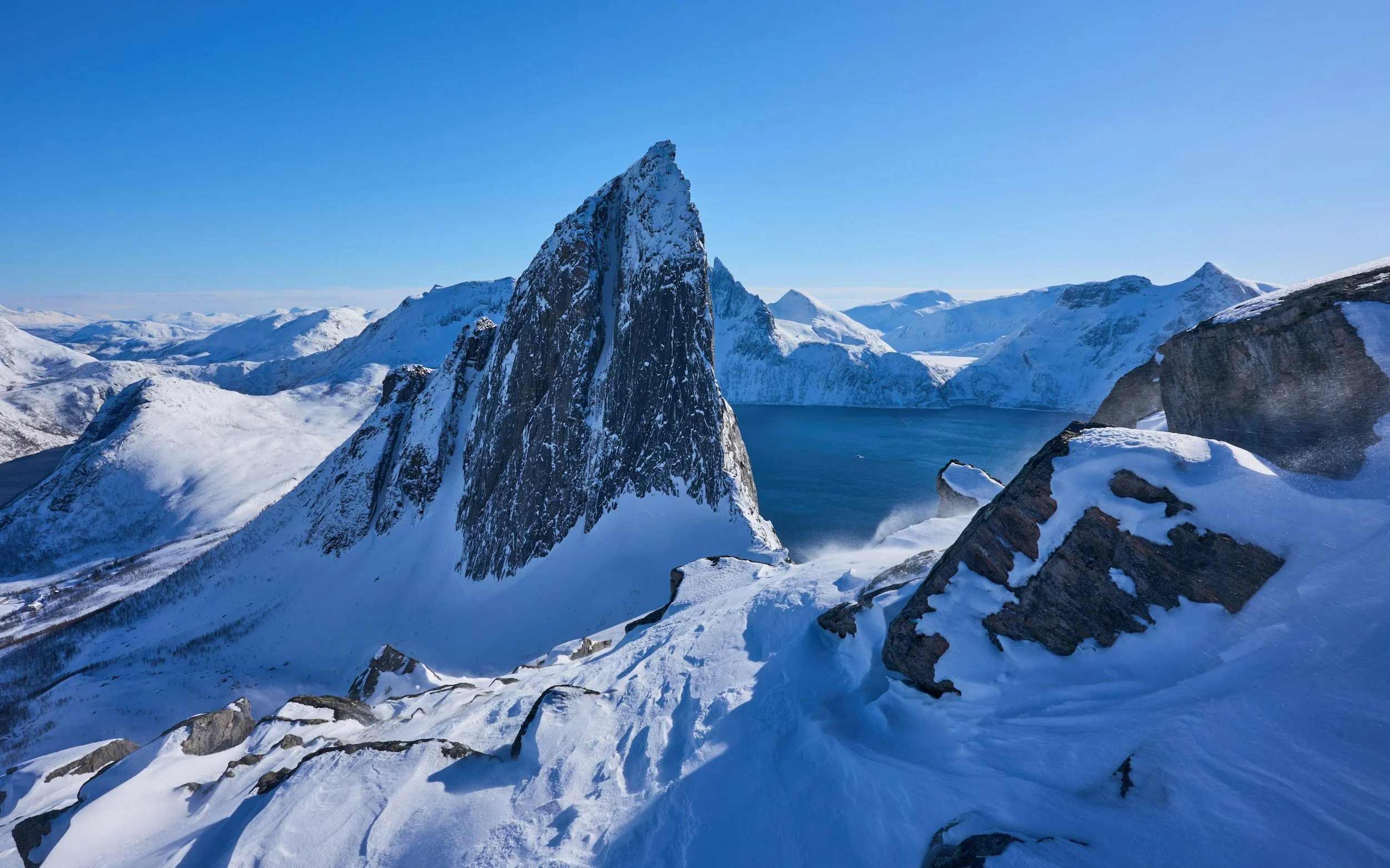 Viewpoint overlooking senja in winter, everything is snowcovered and the light is soft blue.