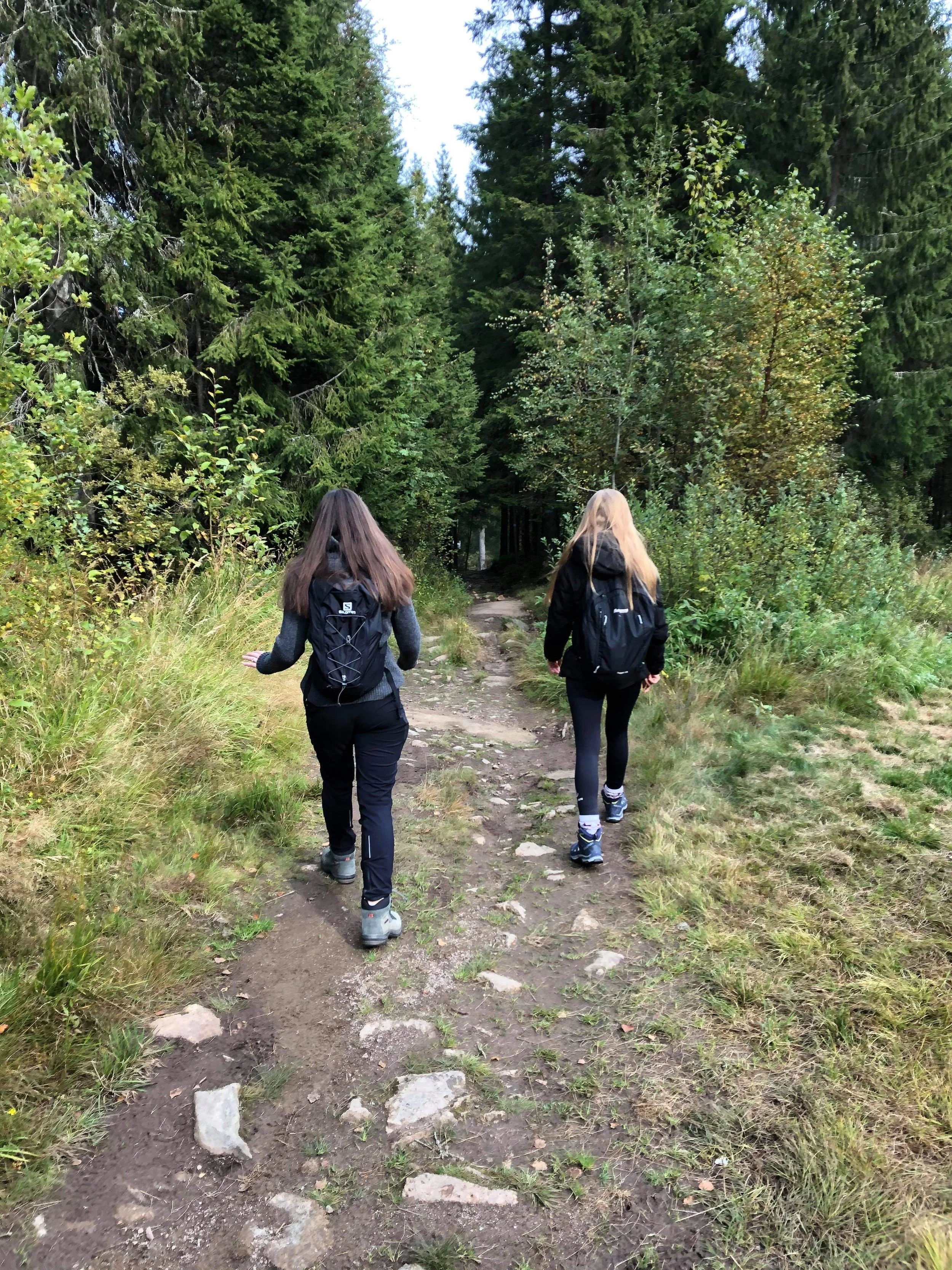 Typical hiking clothing in Norway with layered outfit, hiking boots and small backpack for storing extra layers during a summer hike.