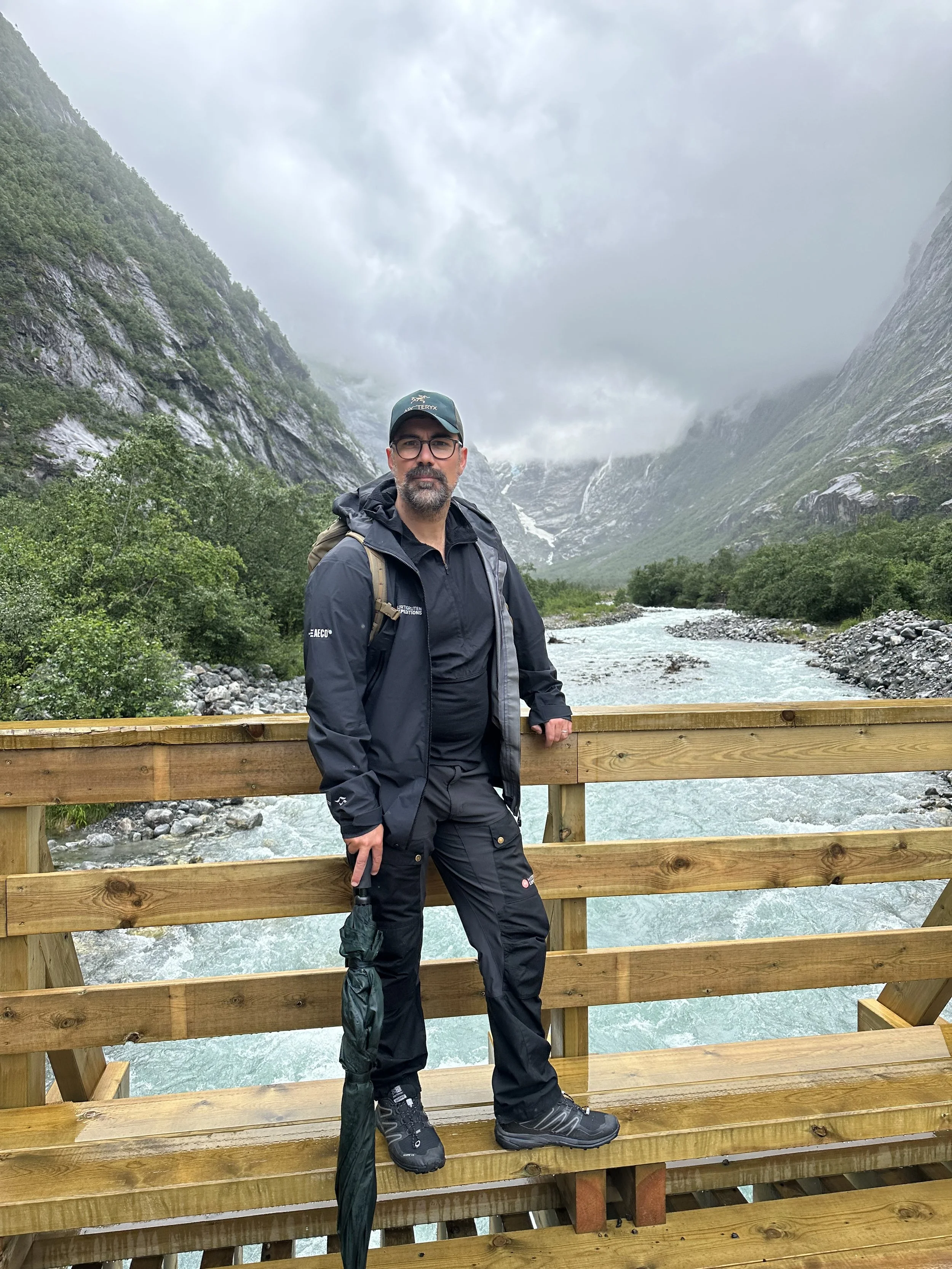 Hiking clothing worn in rainy mountain conditions in Norway, including waterpoof jacket, hiking trousers, backpack and proper footwear.