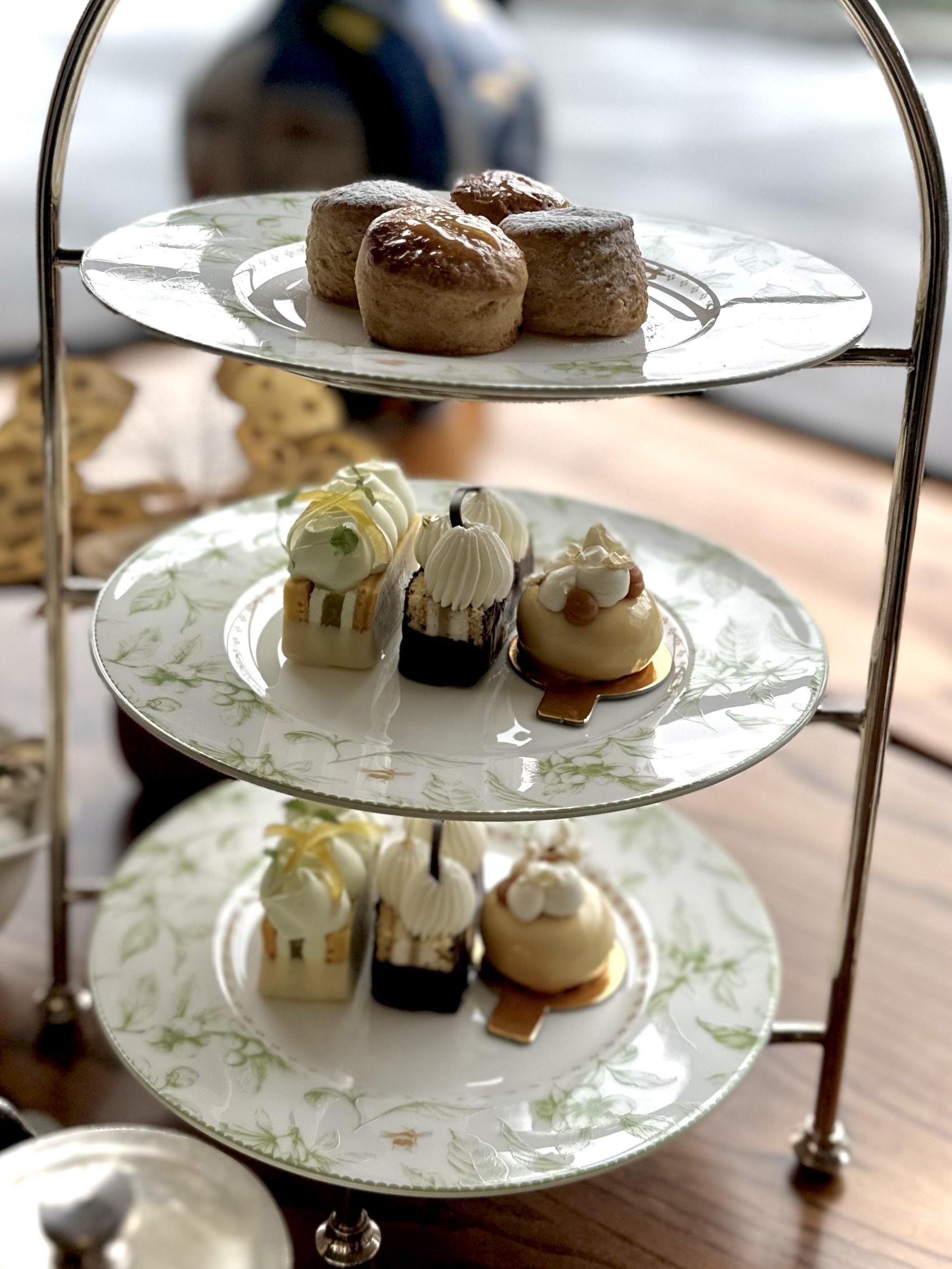 Tiered cake stand with small pastries and cakes served at afternoon tea.