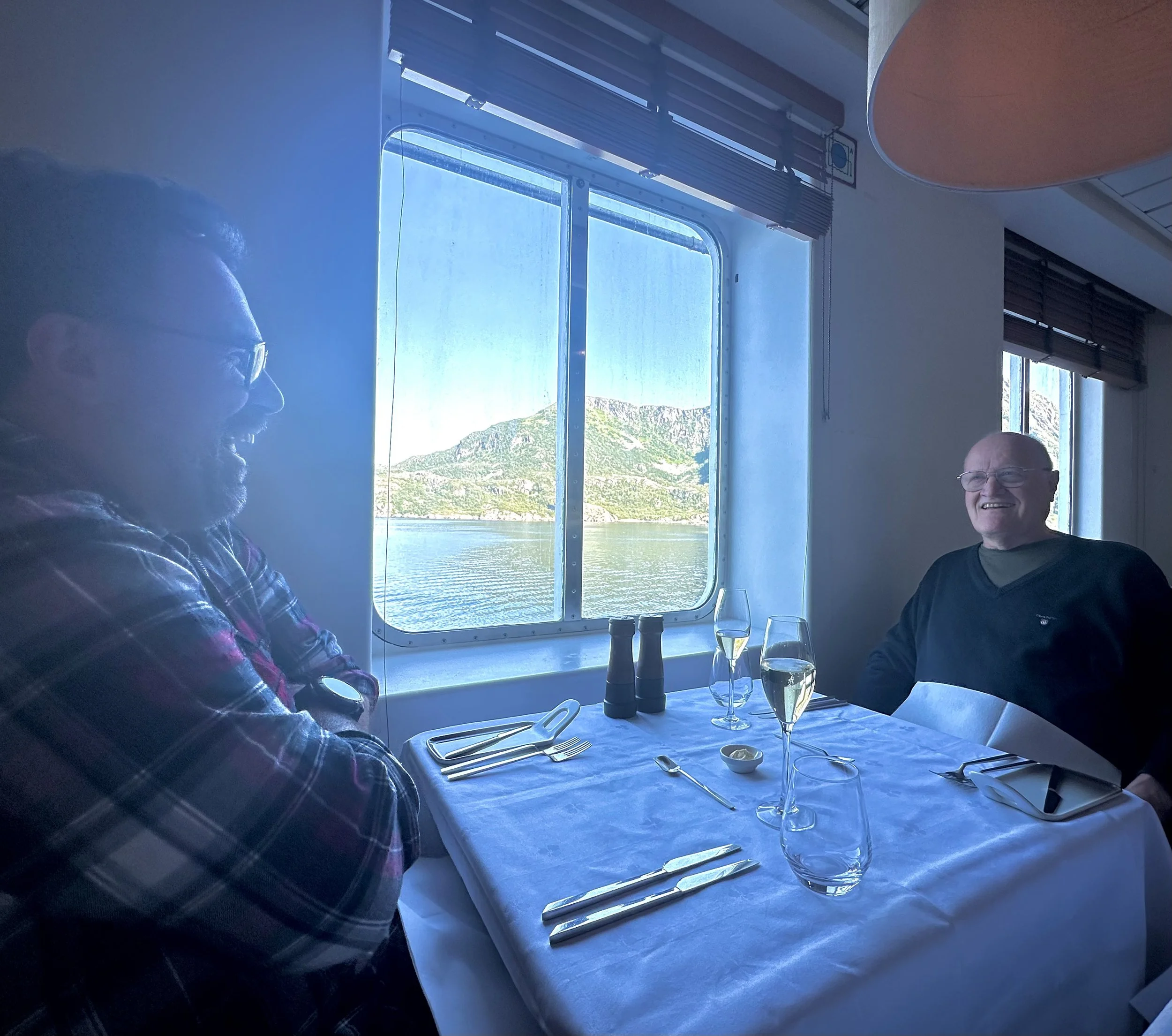 Relaxed onboard dining aboard a Norwegian coastal cruise, where passengers wear practical everyday clothing despite the refined restaurant setting.