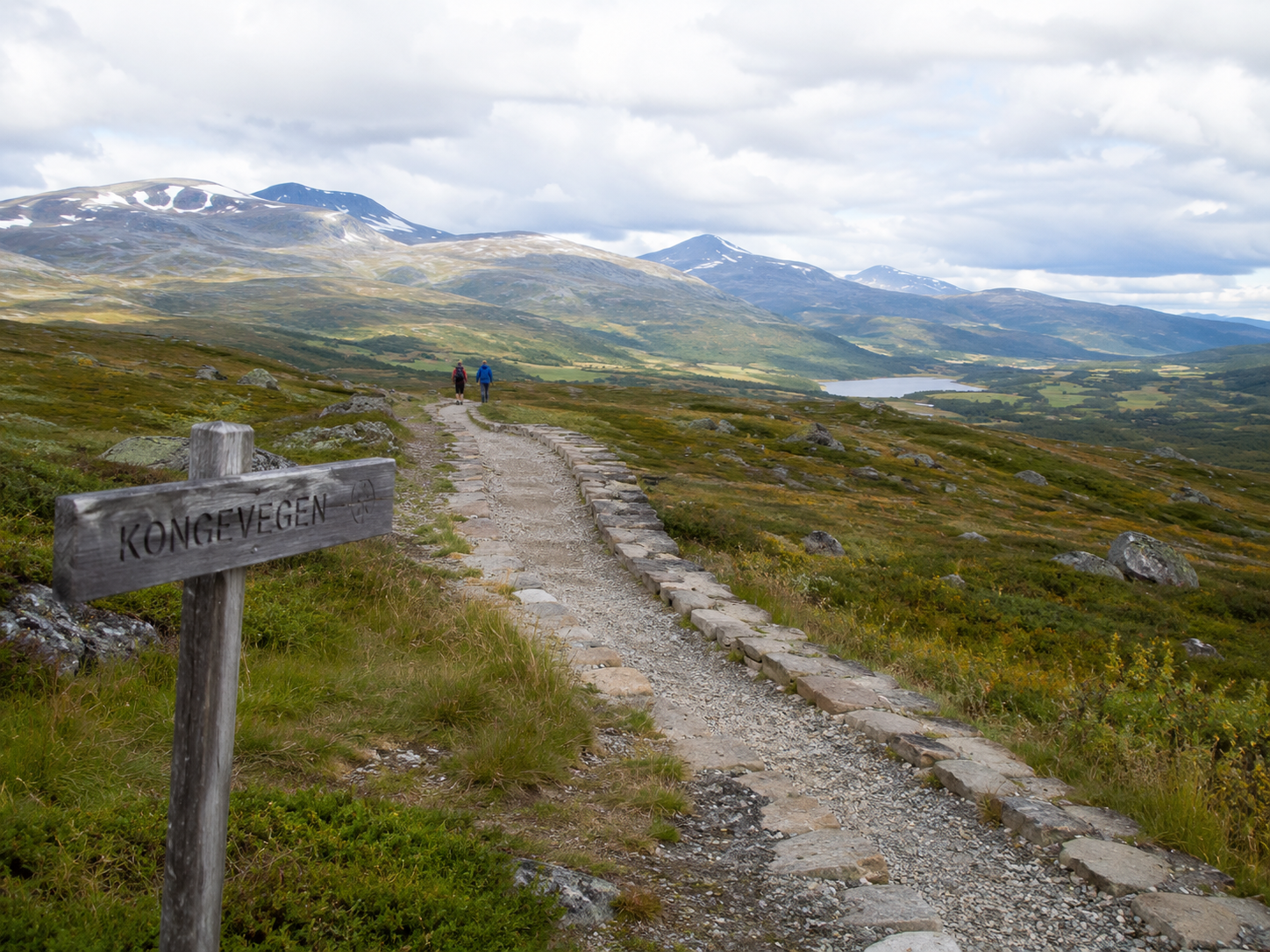 Two hikers walking along the historic King’s Road across Filefjell in Valdres, surrounded by open mountain landscape.