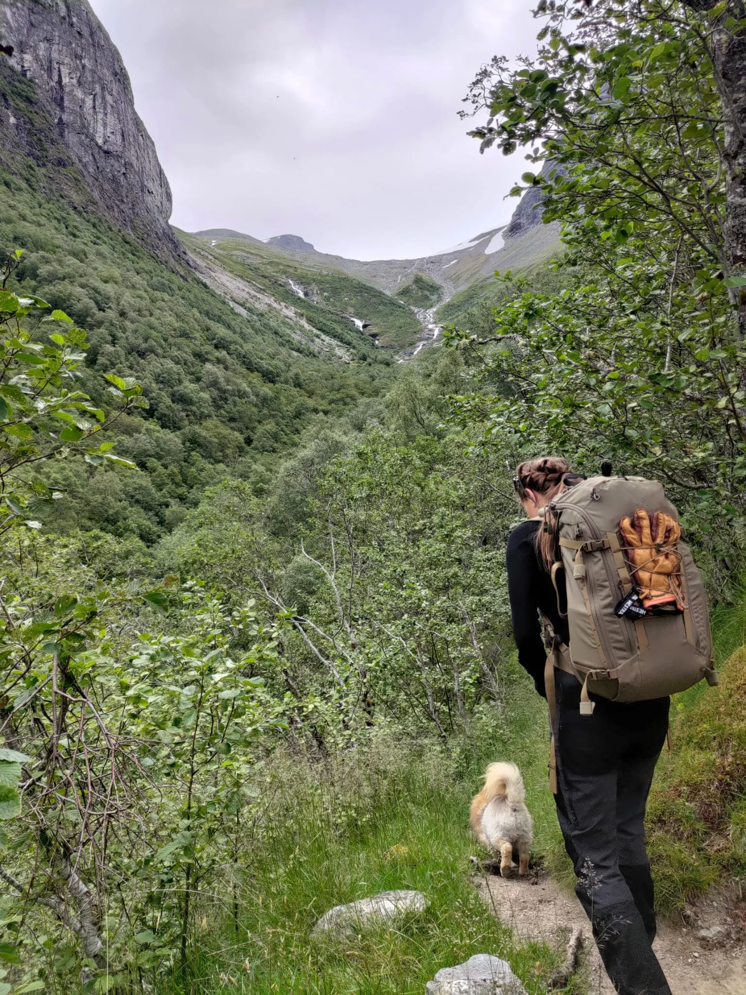 Norwegian summer hiking outfit with backpack on a mountain trail, illustrating practical outdoor clothing used in Norway.