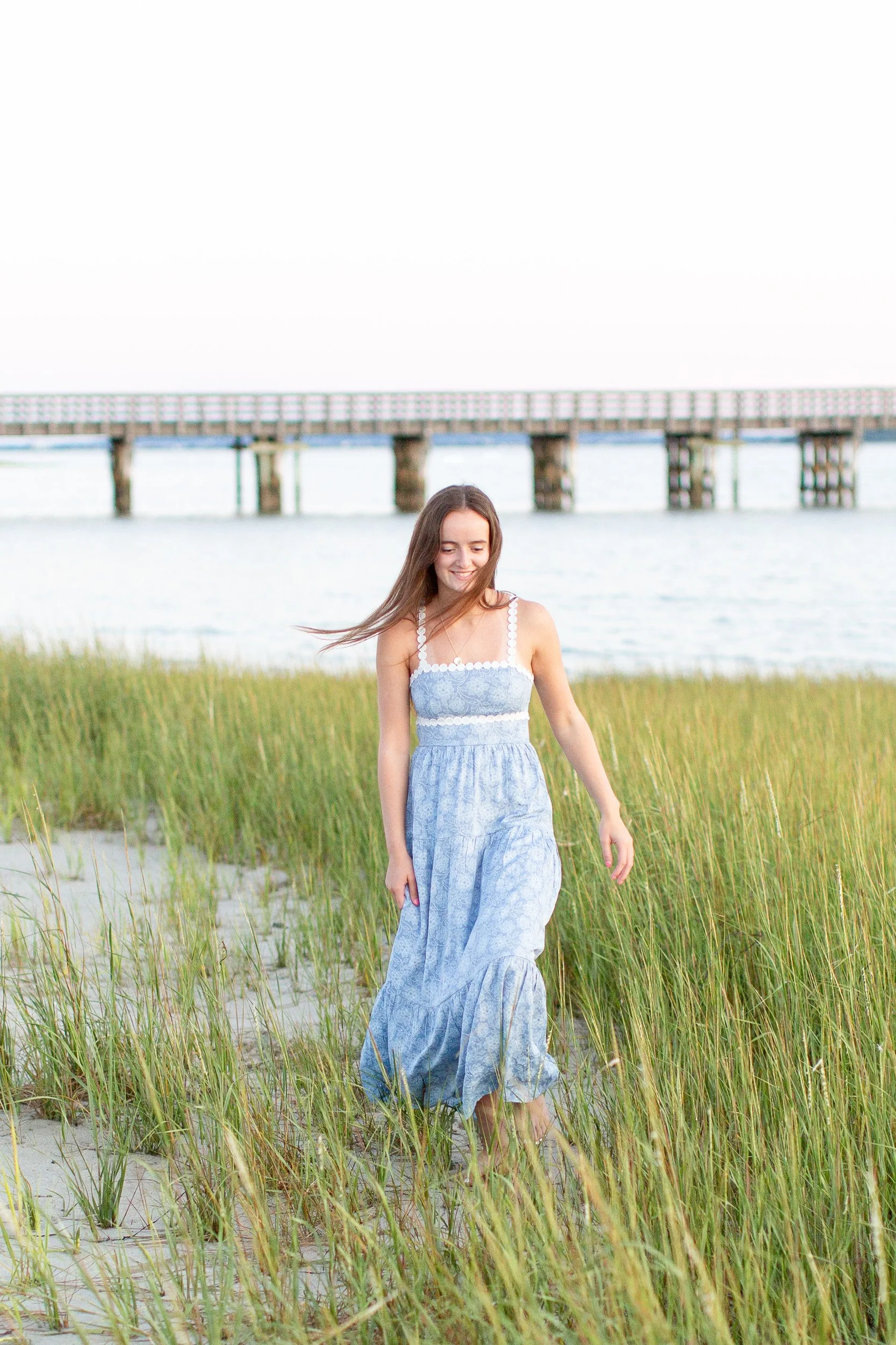 Senior girl in a flowing blue dress during an evening beach session