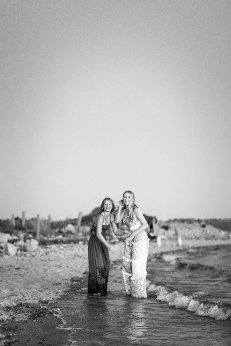 Two high school seniors laughing together during a best friend senior photography session on Duxbury Beach