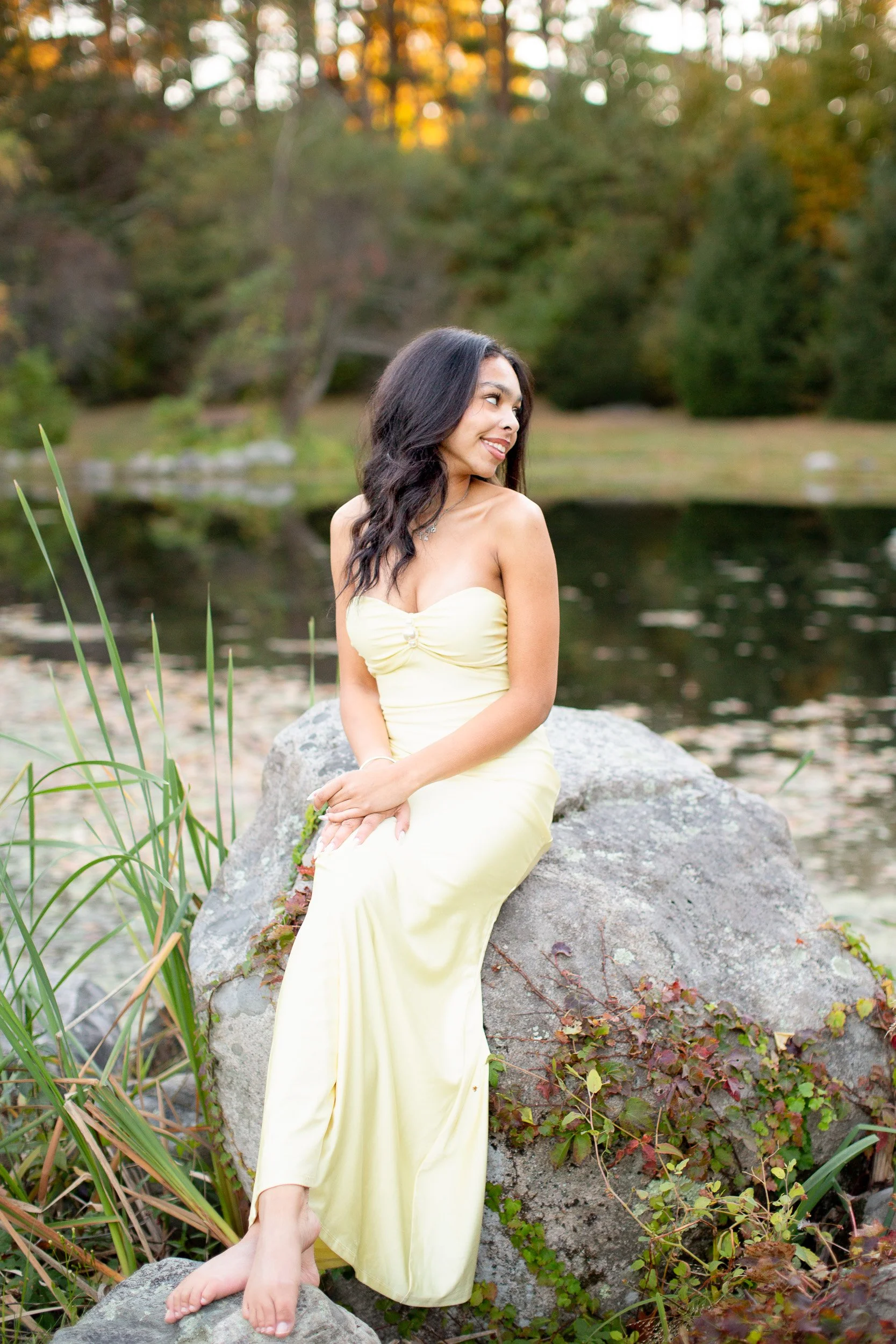 Maya sitting outdoors surrounded by fall greenery during her senior session.