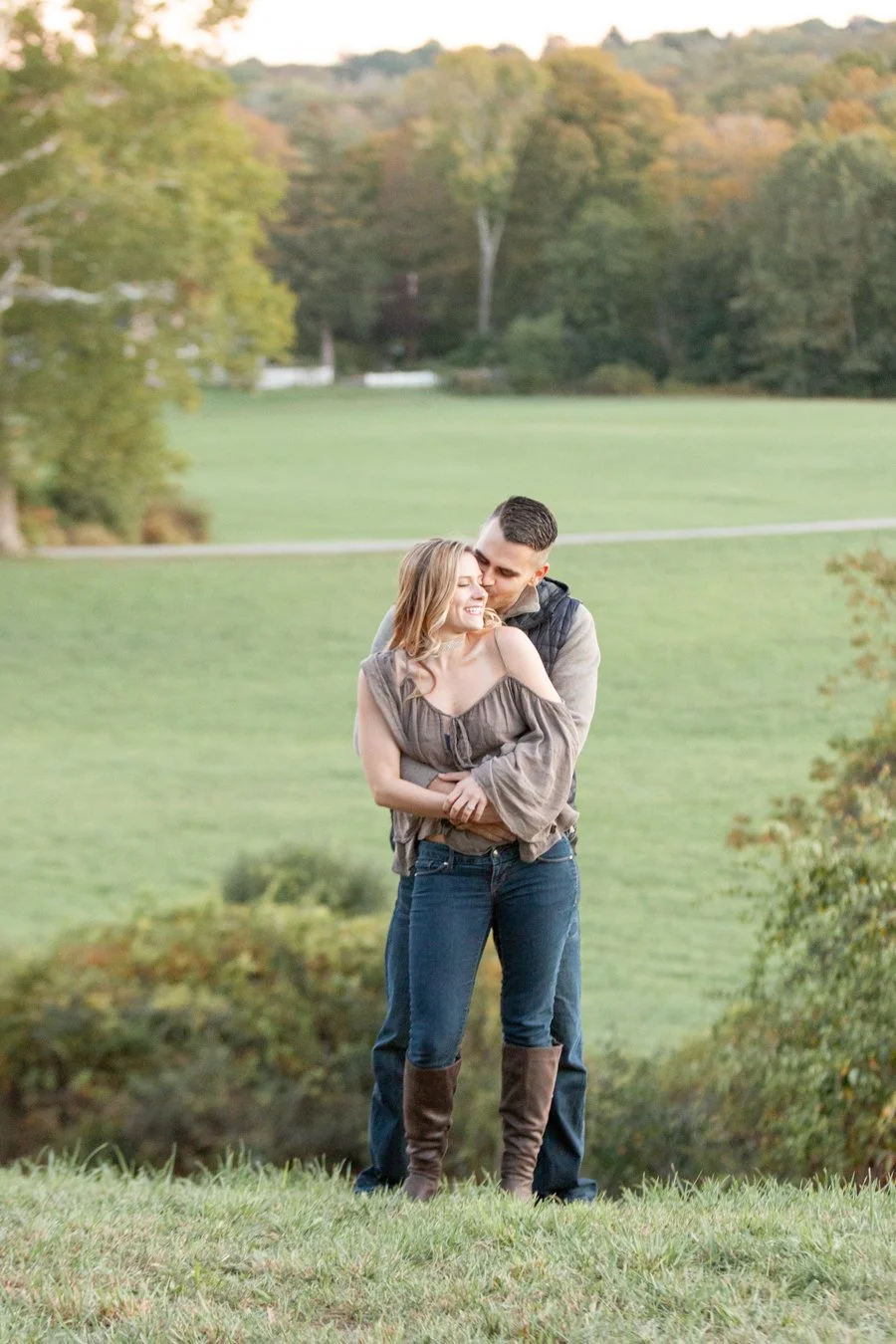 A fun, laughing moment between a couple during their elevated boutique-style engagement session at Chase Farm in Lincoln, RI, photographed by Courtney Wager Photography.