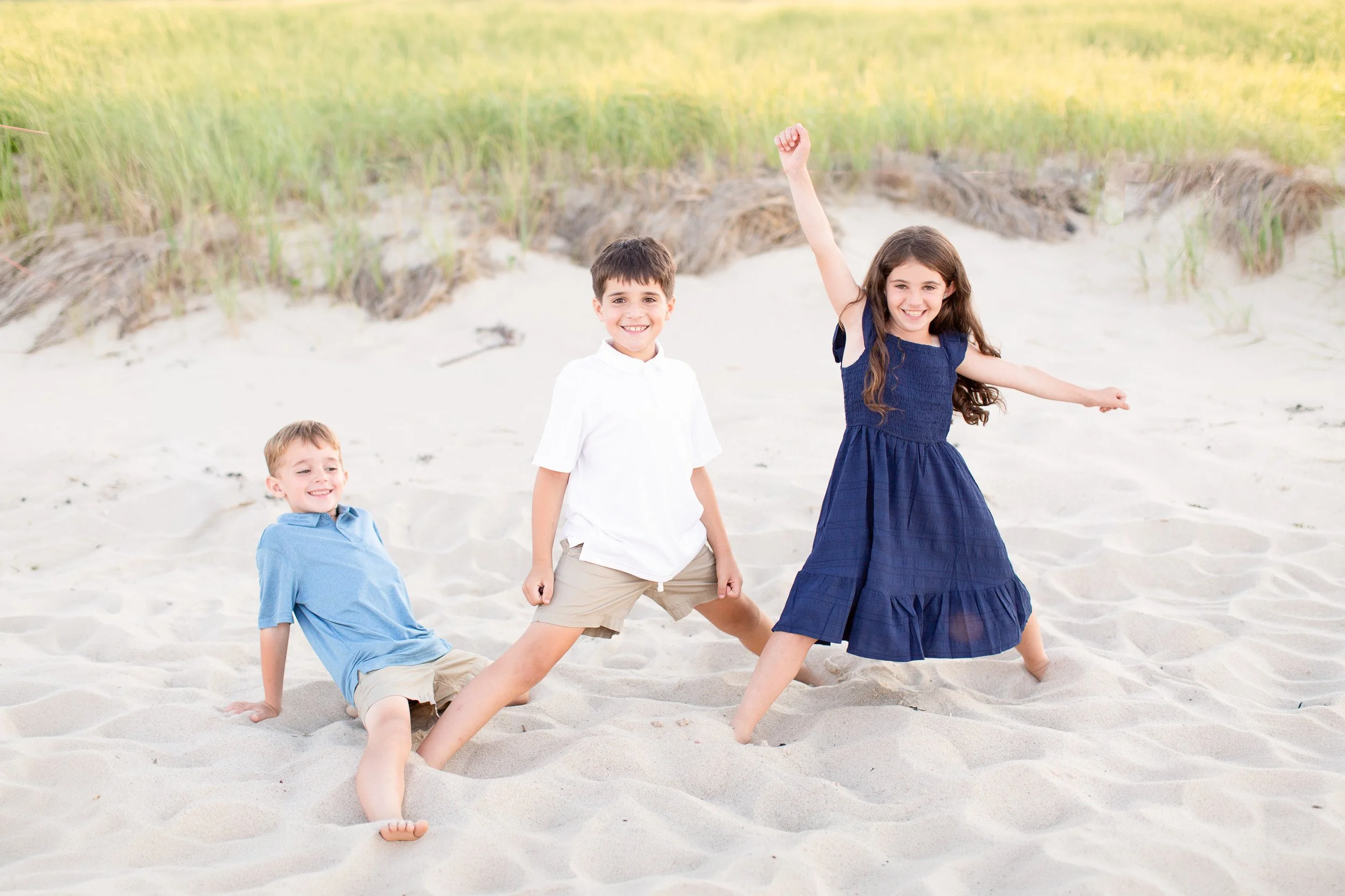 Siblings playing together on the beach during family photos in Sandwich, MA.