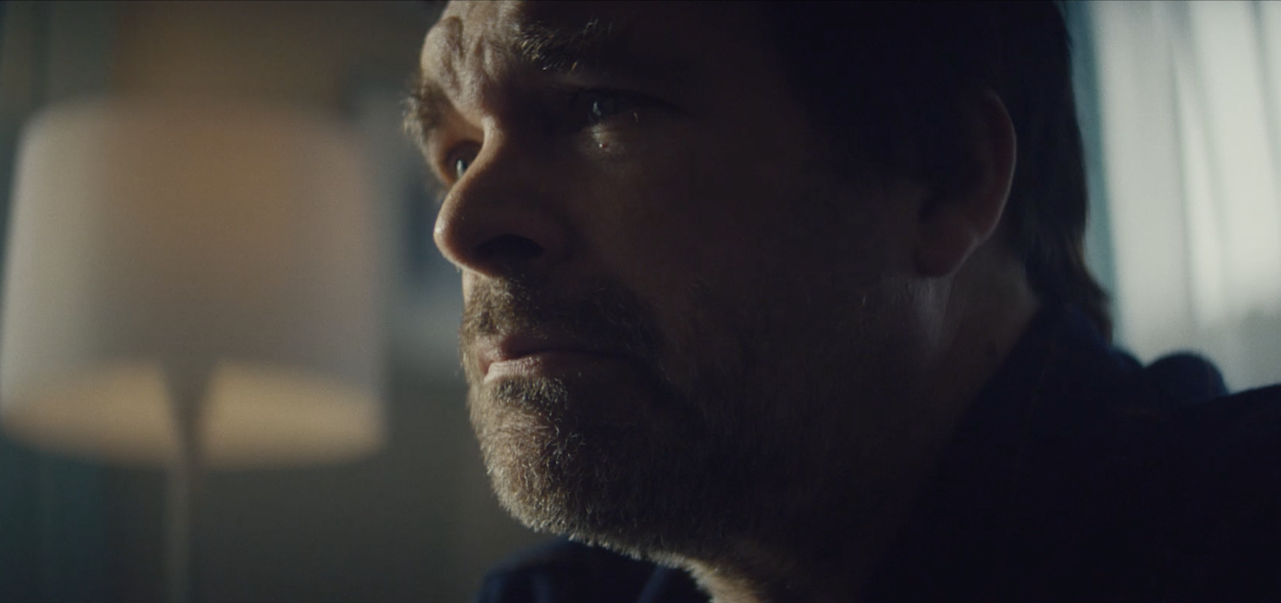 Close-up of a man's face in profile, with a serious expression, lit by natural light from a window.