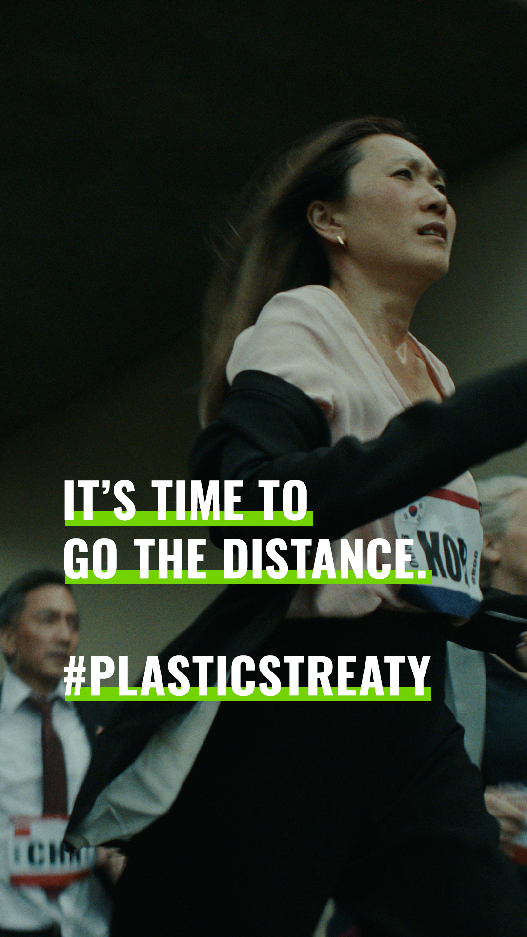A woman running in a marathon, with a man running behind her, and text overlay that says 'It's time to go the distance. #PLASTICSTREATY' n a Greenpeace social campaign.