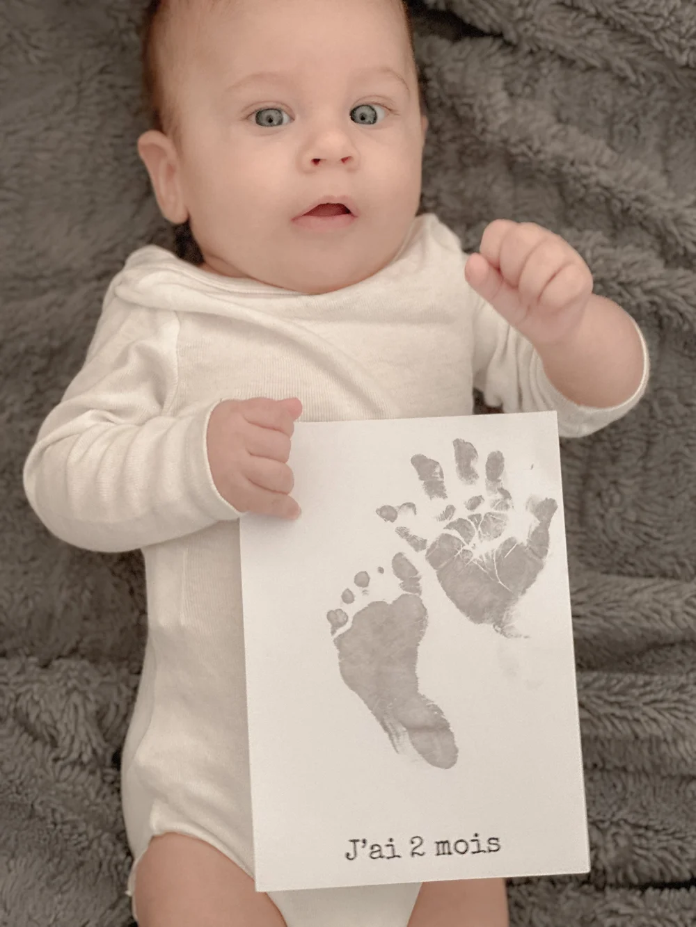 Bébé tenant sa carte d’empreintes de main et de pied Galerie AMKA