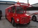 Red vintage delivery van parked next to a modern bus.
