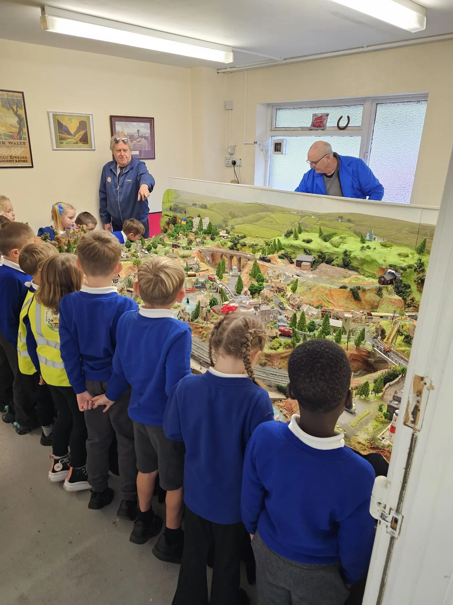 A red double-decker bus with passengers on the top deck, traveling near trees. The bus has a destination sign that reads 'Caswell Bay' and the branding 'South Wales' on the side.