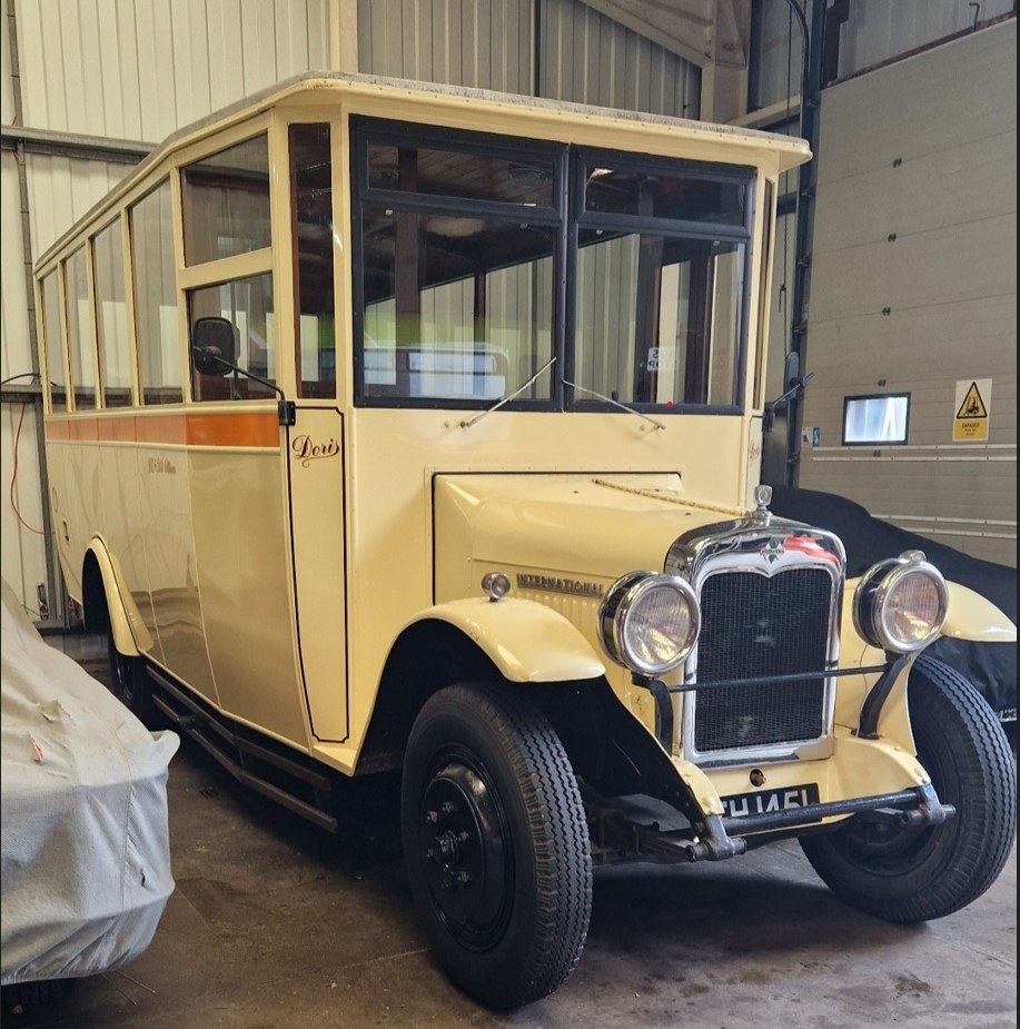 Vintage cream-colored bus with black accents parked inside a warehouse.