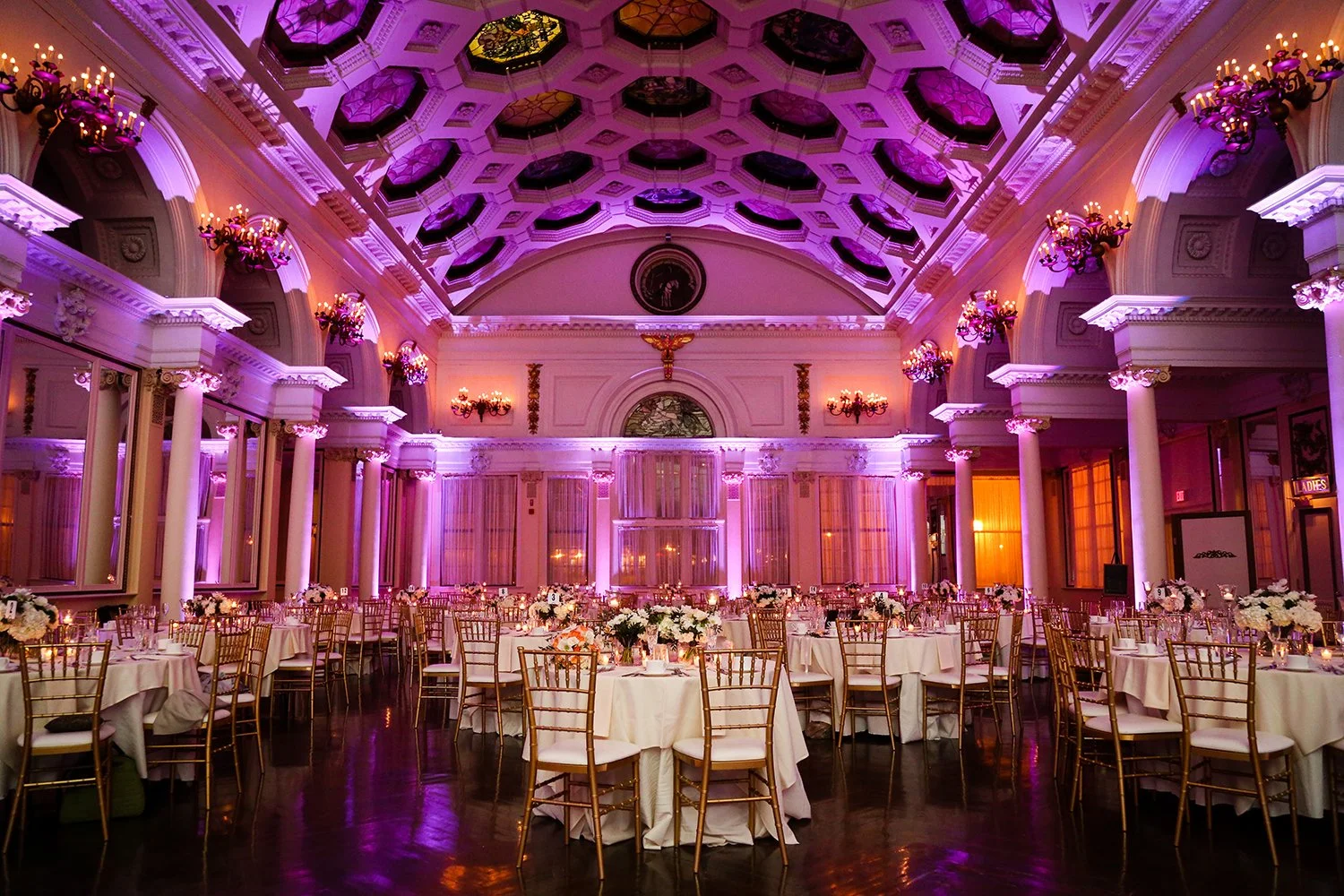 Colorful uplights in purple, and blue shining down in a wedding setting.