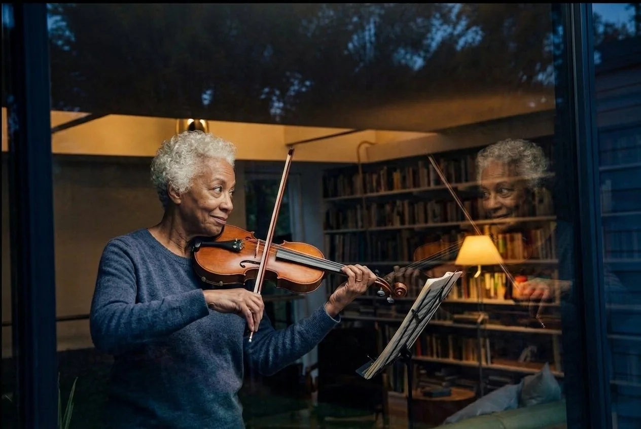 Adult violinist practising at home and watching her reflection in a window while noticing tension in her left hand and shoulder.
