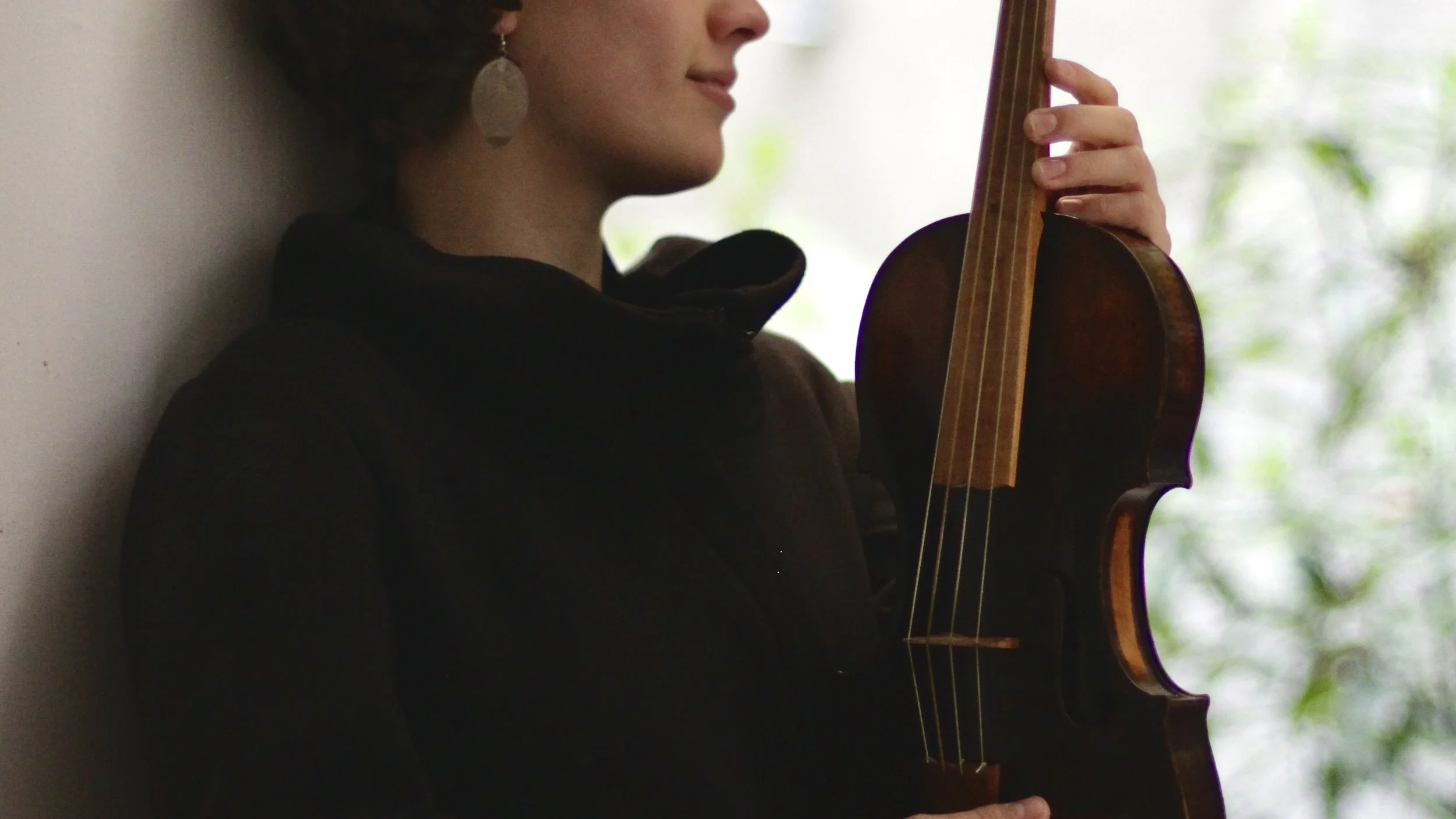 Adult violinist holding a violin in a relaxed, historically informed setup, pausing to feel balance and freedom in the instrument.