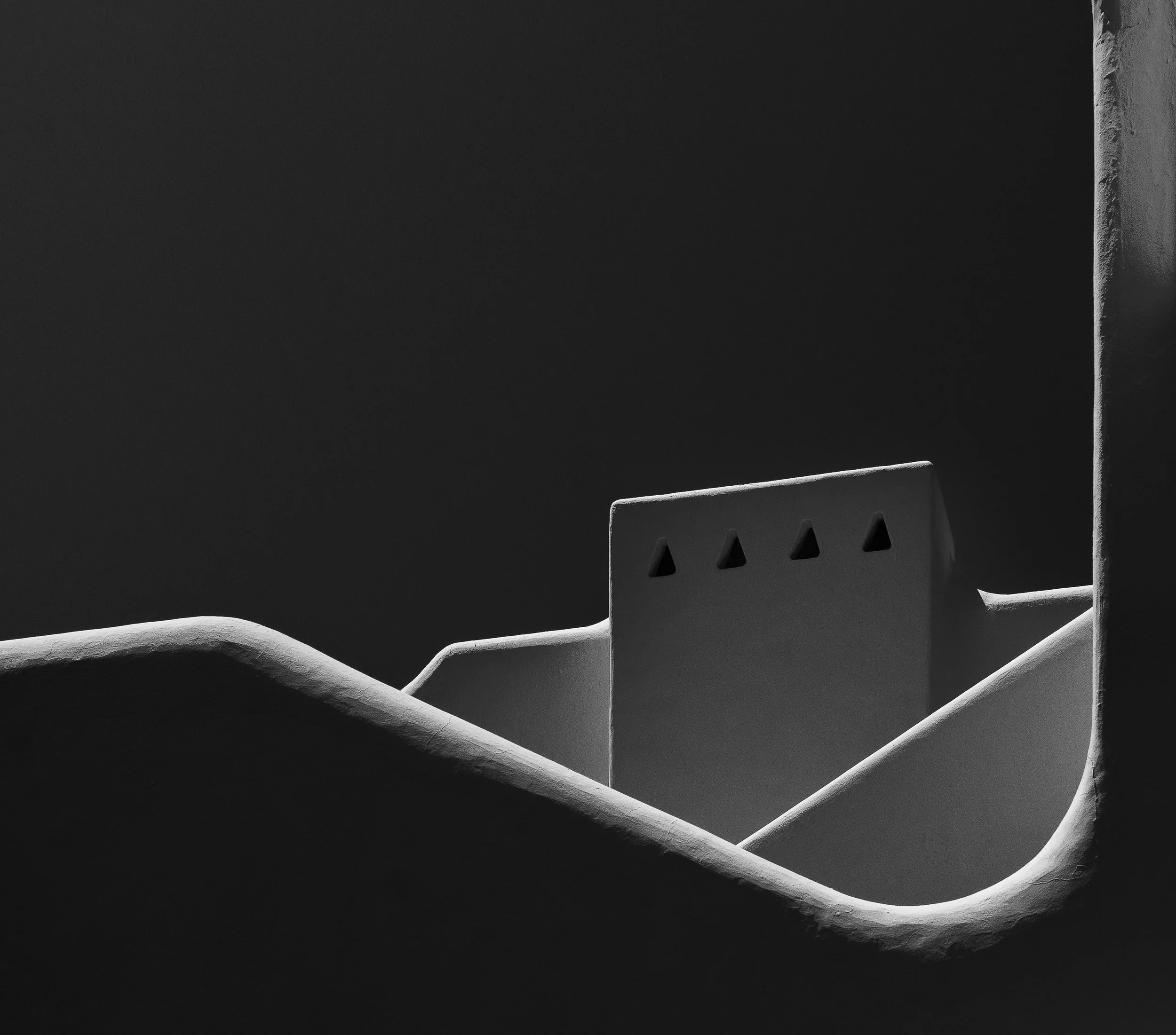 Schwarze und weiße Fotografie eines Gebäudes in Santorini mit traditionellen weiß getünchten Wänden und einer klaren, dunklen Nacht im Hintergrund.