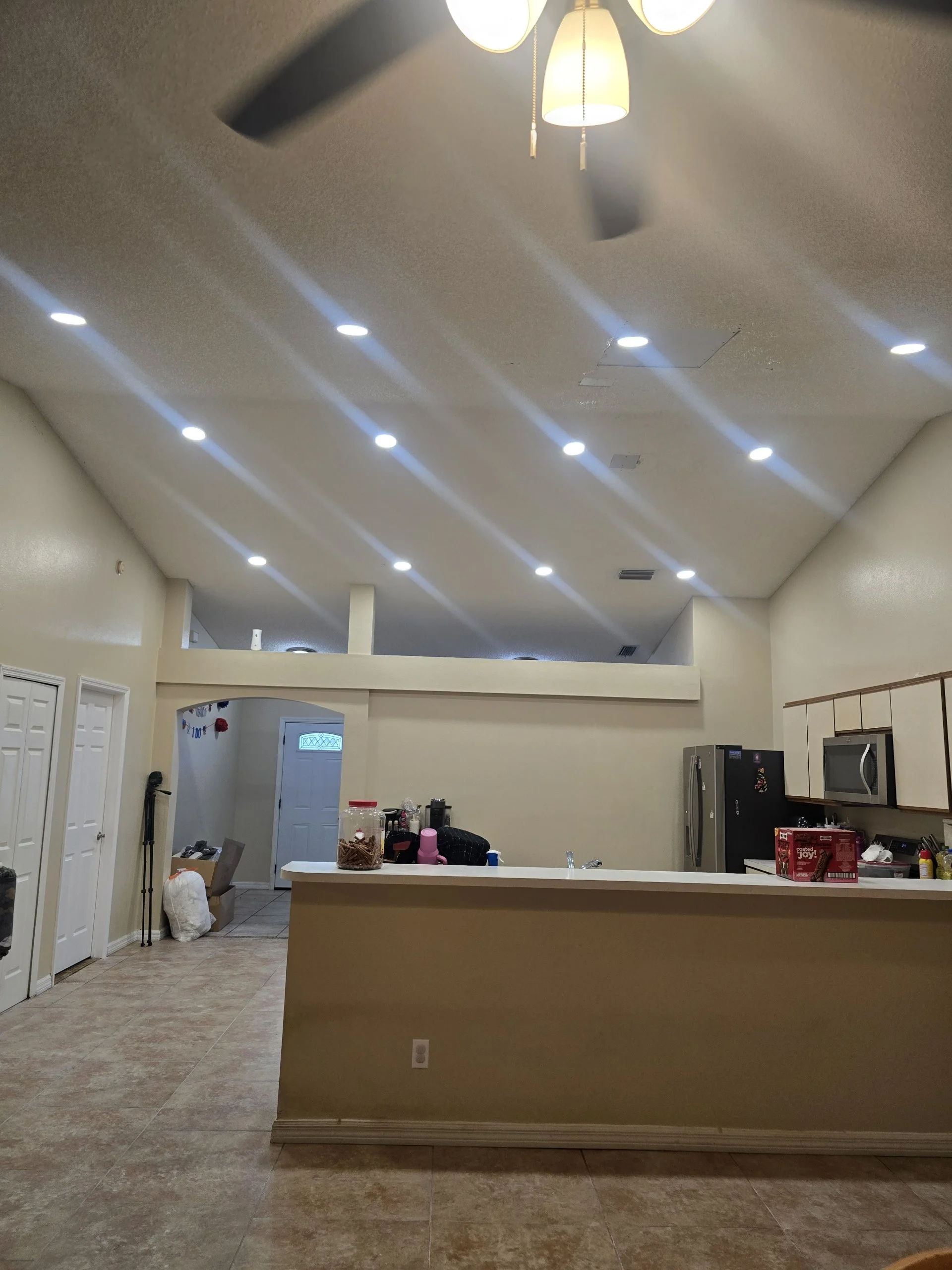 Interior of a house with a kitchen, visible ceiling fan, recessed lighting, and an open layout.