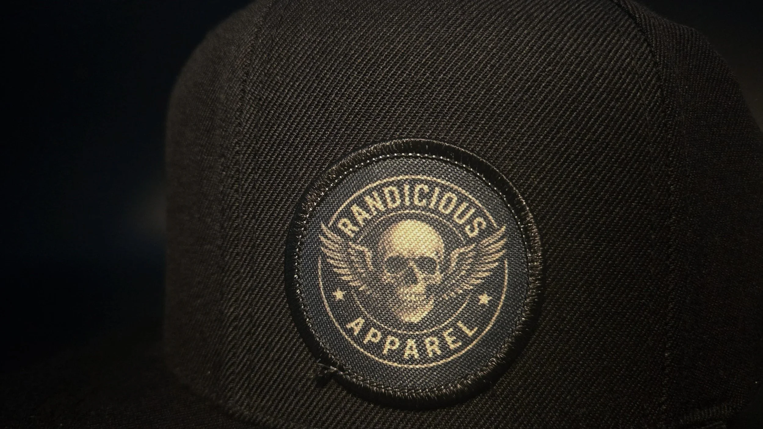 Close-up of stitched Randicious skull patch on black snapback hat