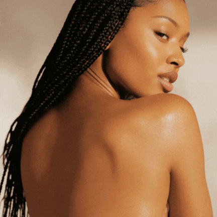 A woman with braided hair is turning her head to the side, showing her shoulder and face with a neutral expression.