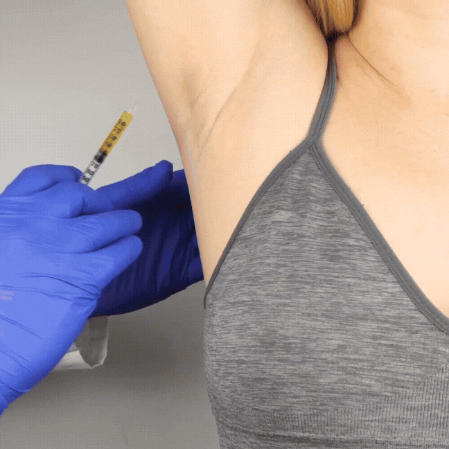 A person receiving a vaccine shot in their upper arm from a healthcare worker wearing blue gloves.