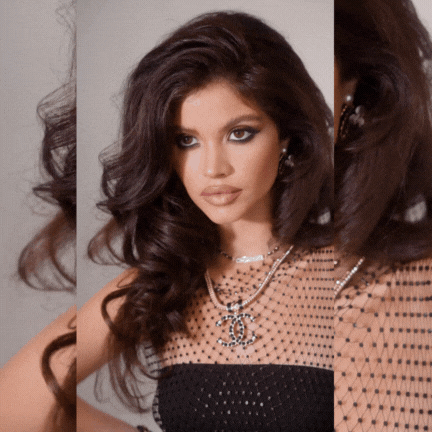 Portrait of a woman with dark, curly hair wearing makeup, diamond jewelry, and a black and beige polka dot dress.