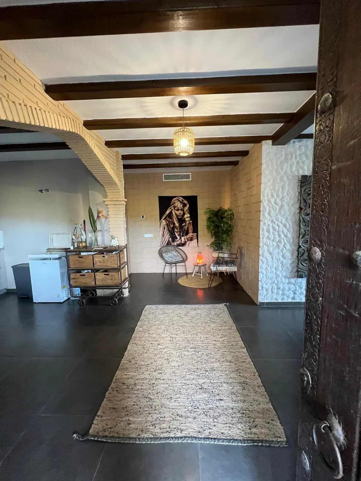 Ingang van een hotelreceptie met een houten balie, decoratieve muurpanelen, een mededelingbord, en een lopend tapijt op de vloer.