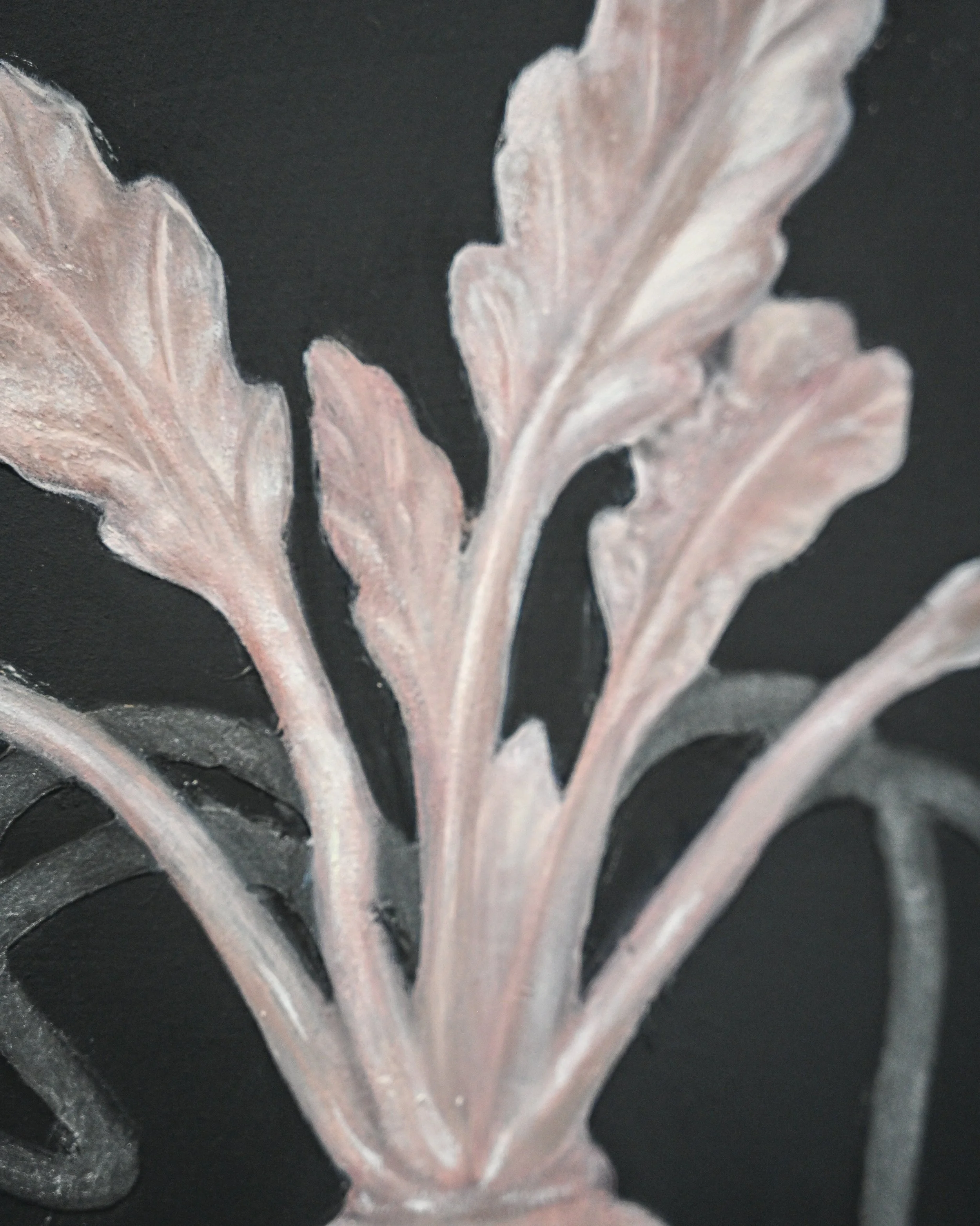 Close-up of a decorative metal floral pattern with pinkish-bronze leaves and stems on a black background.