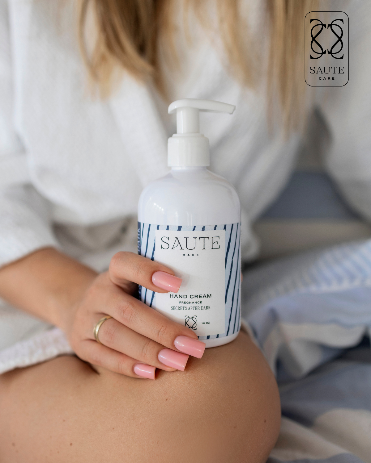 Una donna tiene in mano un flacone di crema per le mani con un erogatore a pompa, scritto 'SAUTE CARE HAND CREAM'.